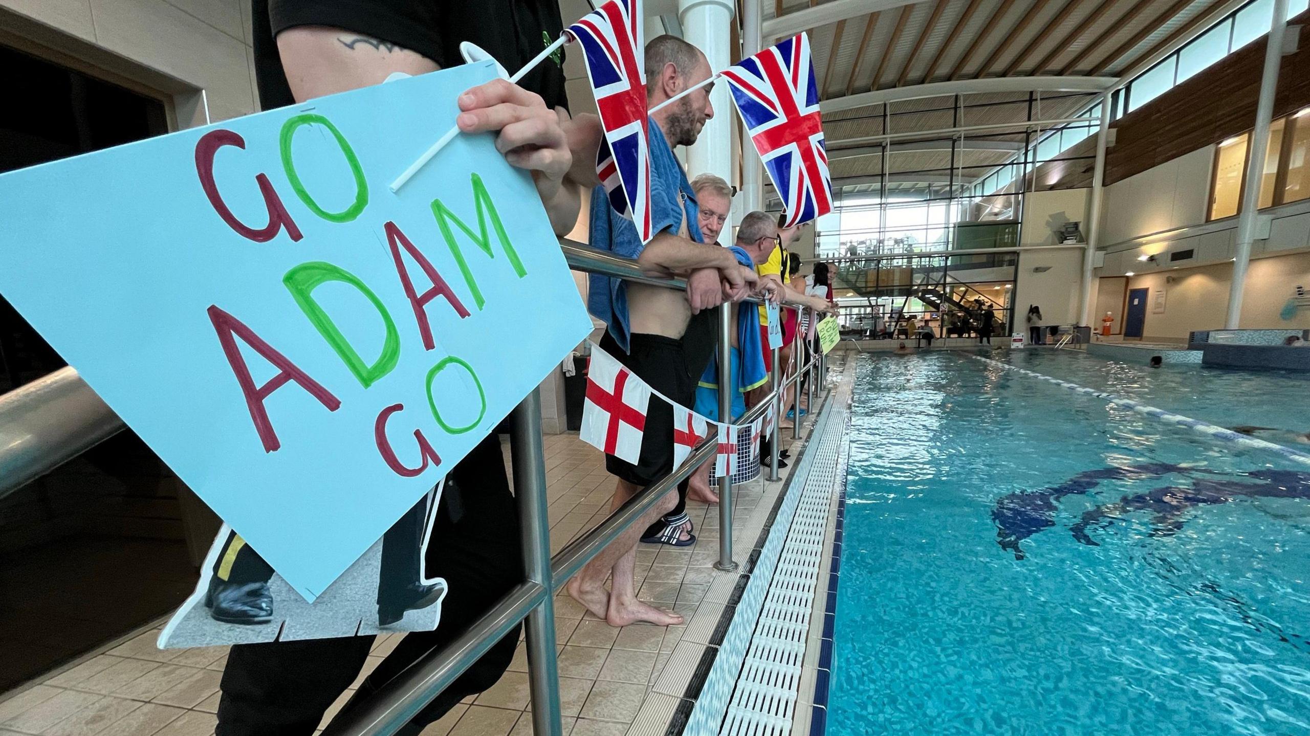 A Go Adam Go sign held by spectators at Nuffield Health swimming pool