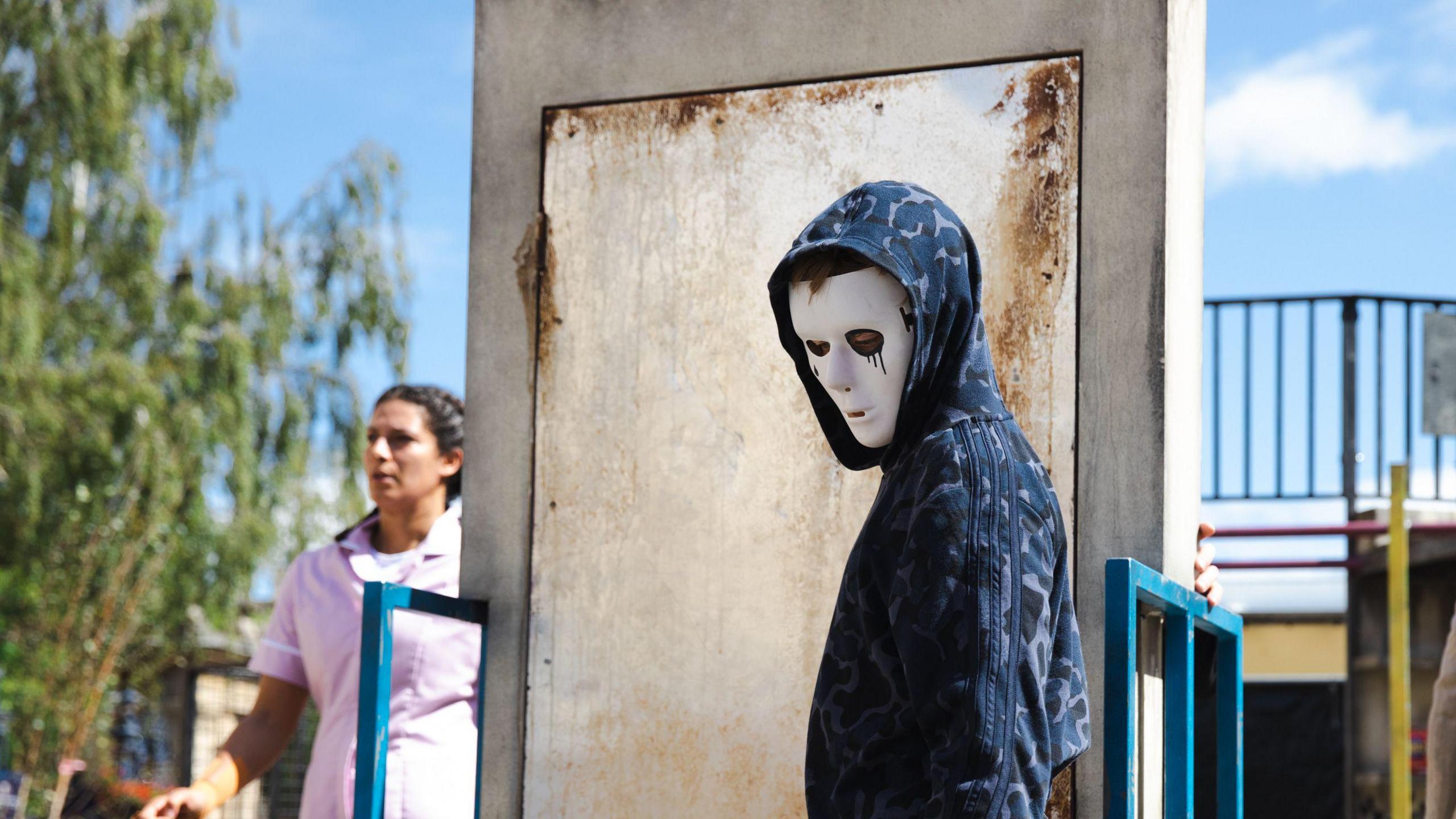 Hooded man wearing white face mask