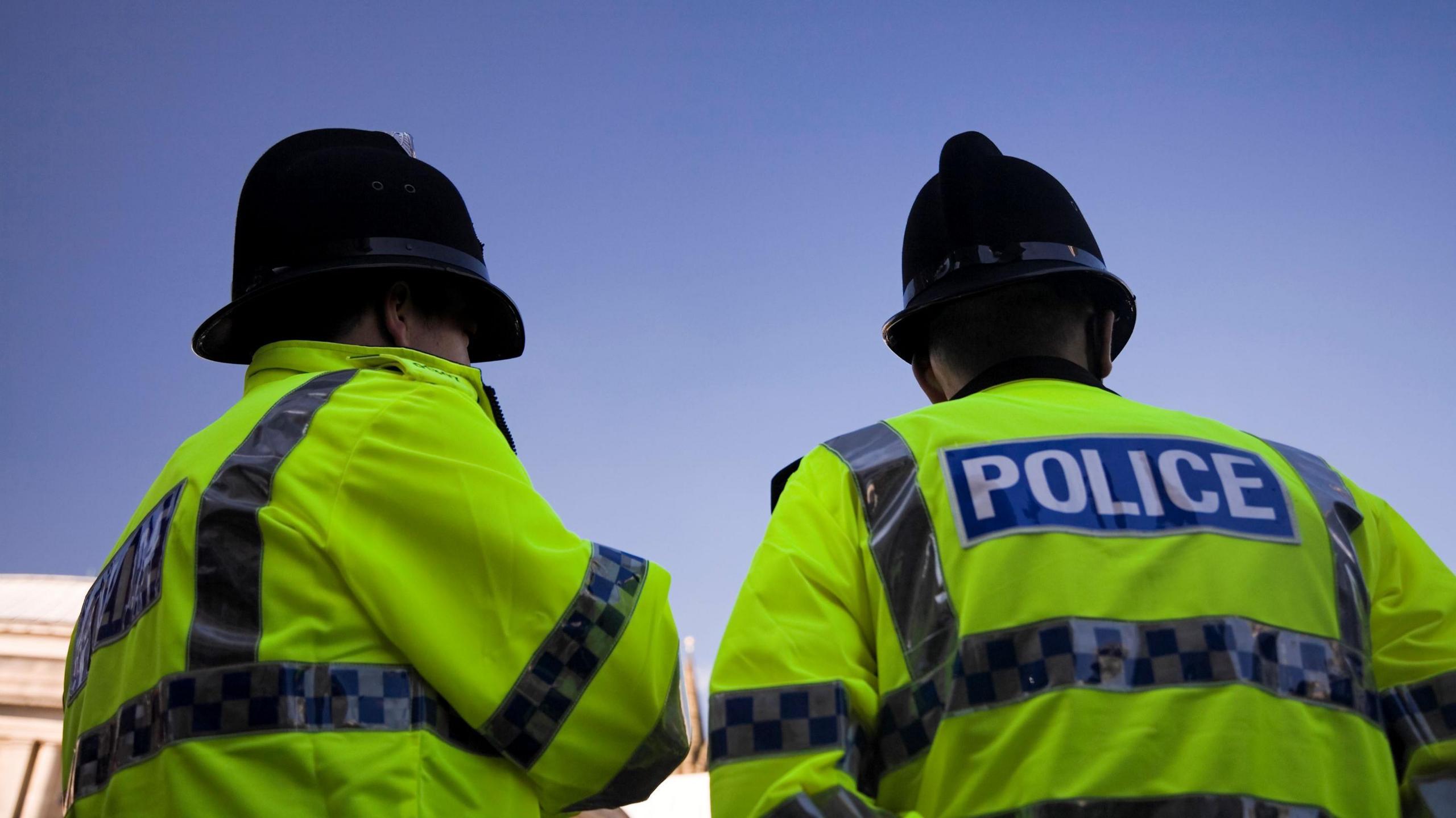 Two male police officers photographed from behind