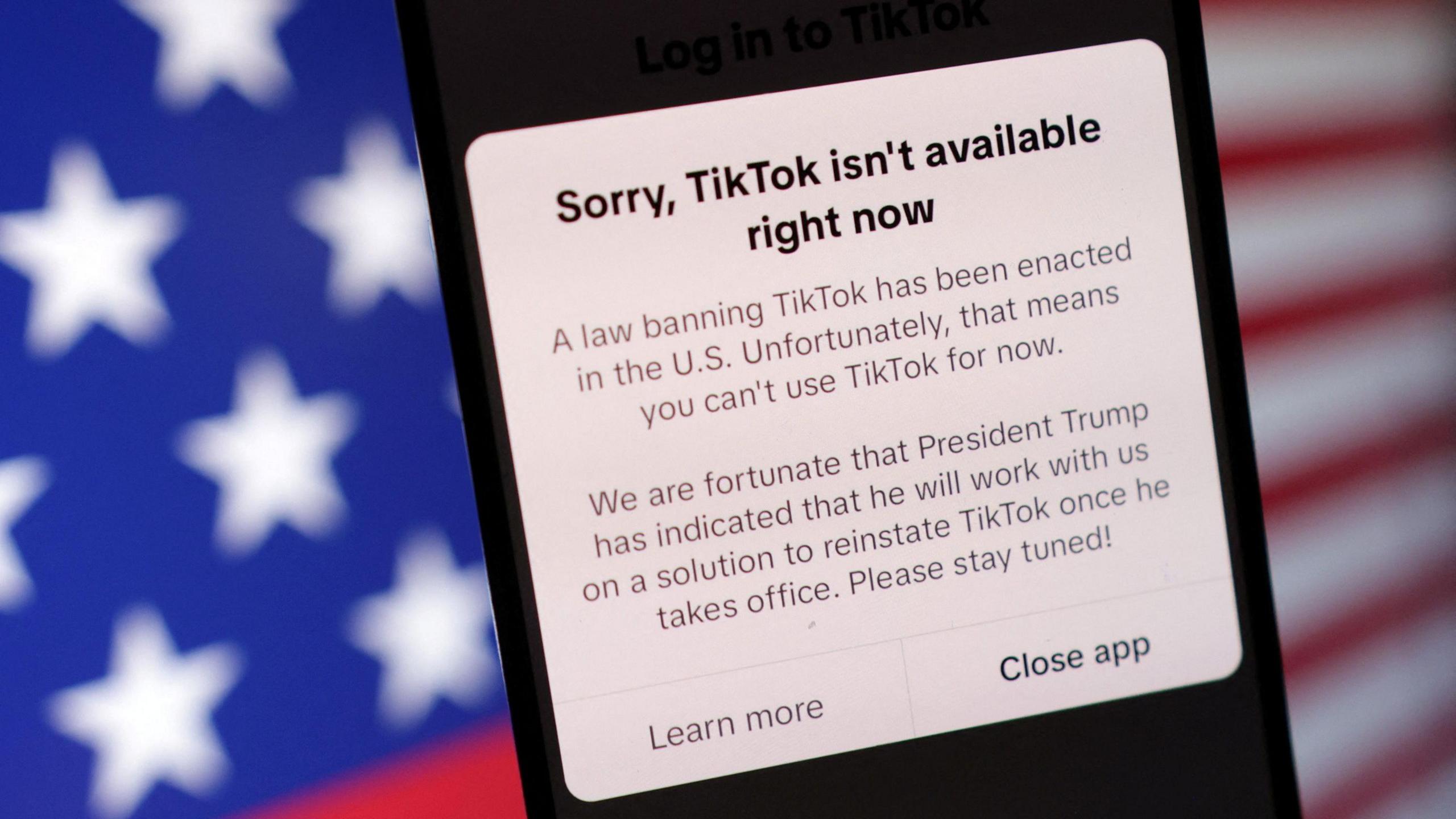 A phone screen that reads: Sorry, TikTok isn't Available right now. A law banning TikTok has been enacted in the US. Unfortunately, that means you can't use TikTok for now. We are fortunate that President Trump has indicated that he will work with is on a solution to reinstate TikTok once he takes office. Please stay tuned!