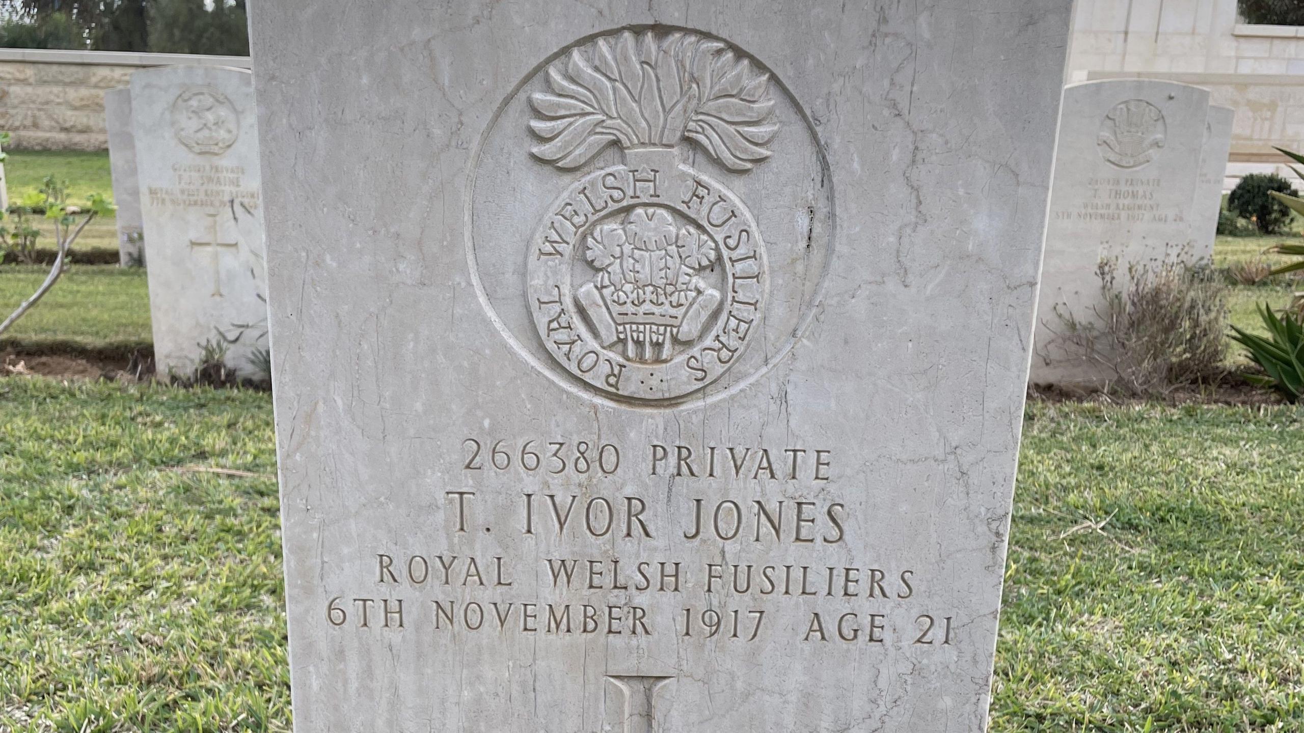 A white headstone in a cemetery with the inscription "T Ivor Jones, Royal Welsh Fusiliers" on it.