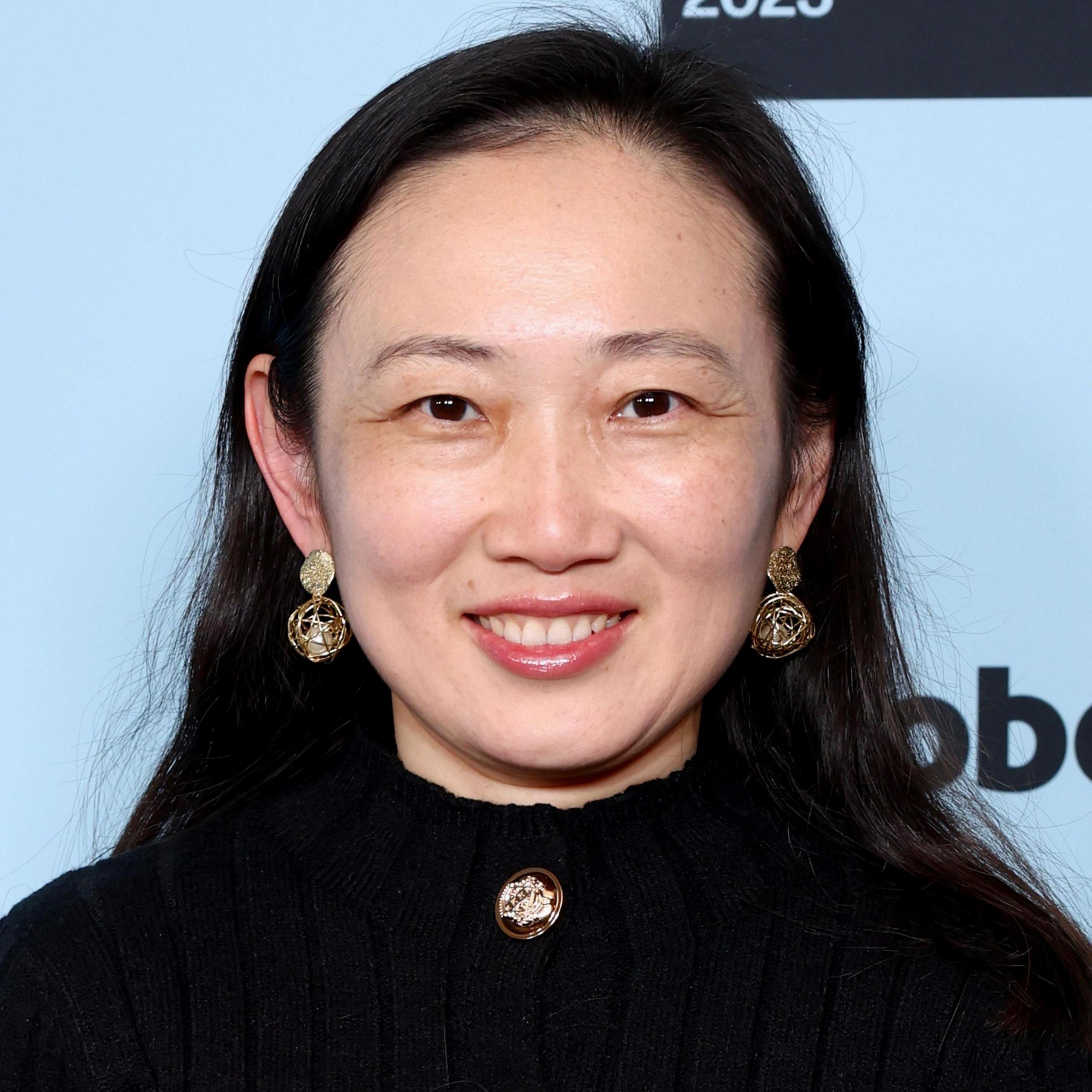 Violet Du Feng, smiling in a black suit