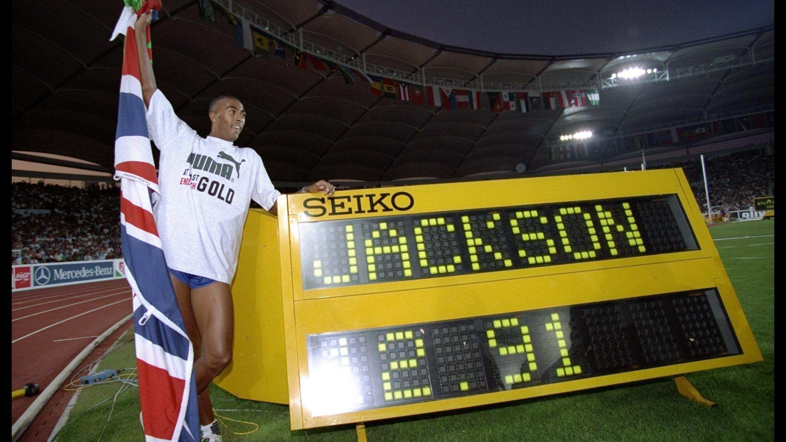 Aug 1993: Colin Jackson of Great Britain holds aloft the union jack and stands next to a clock after his victory in the 110m hurdles final with a new world record of 12.91 seconds during the athletics world championships in Stuttgart, Germany.