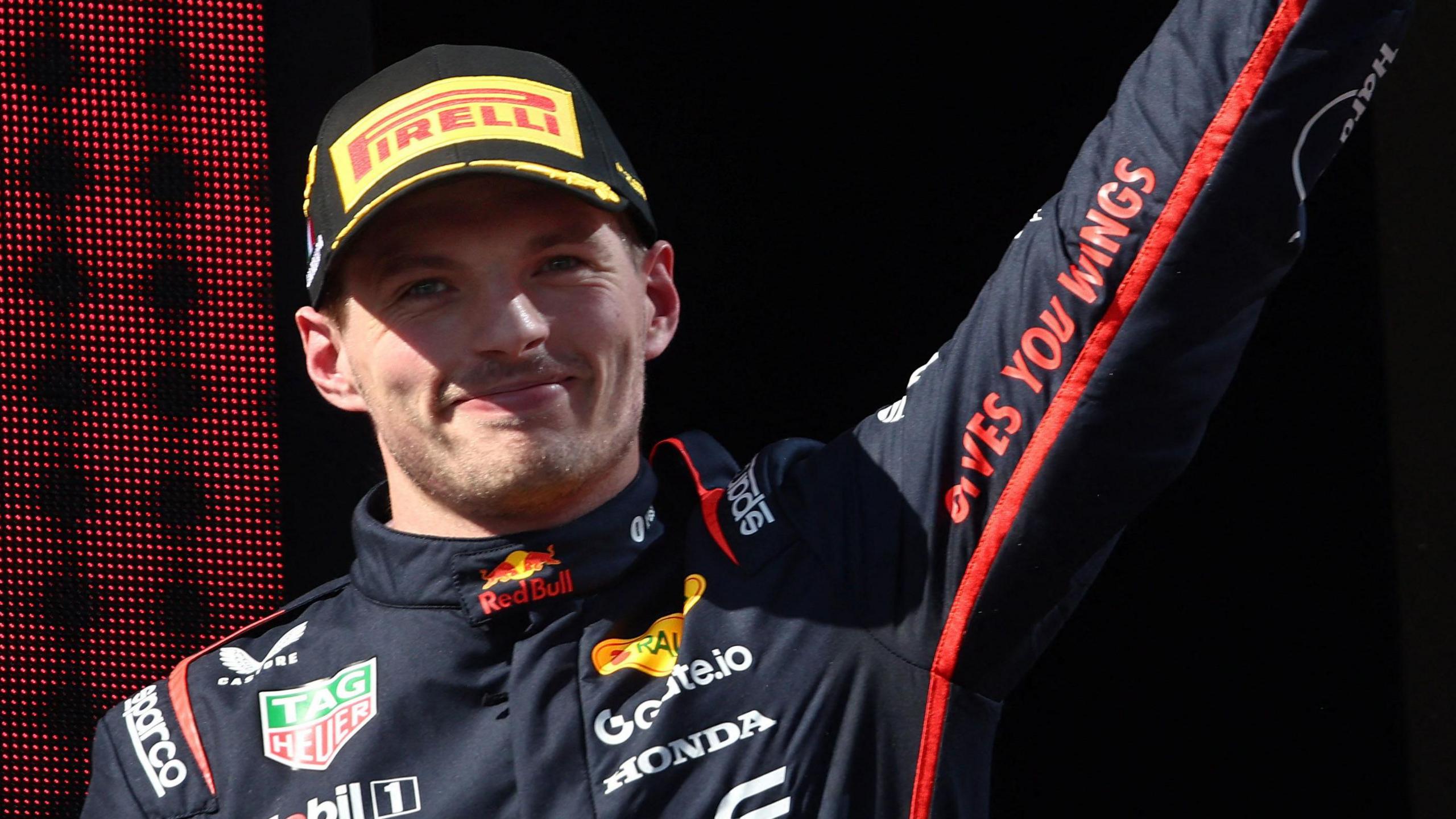 Max Verstappen raises his left arm in celebration on the podium after winning the Emilia-Romagna Grand Prix