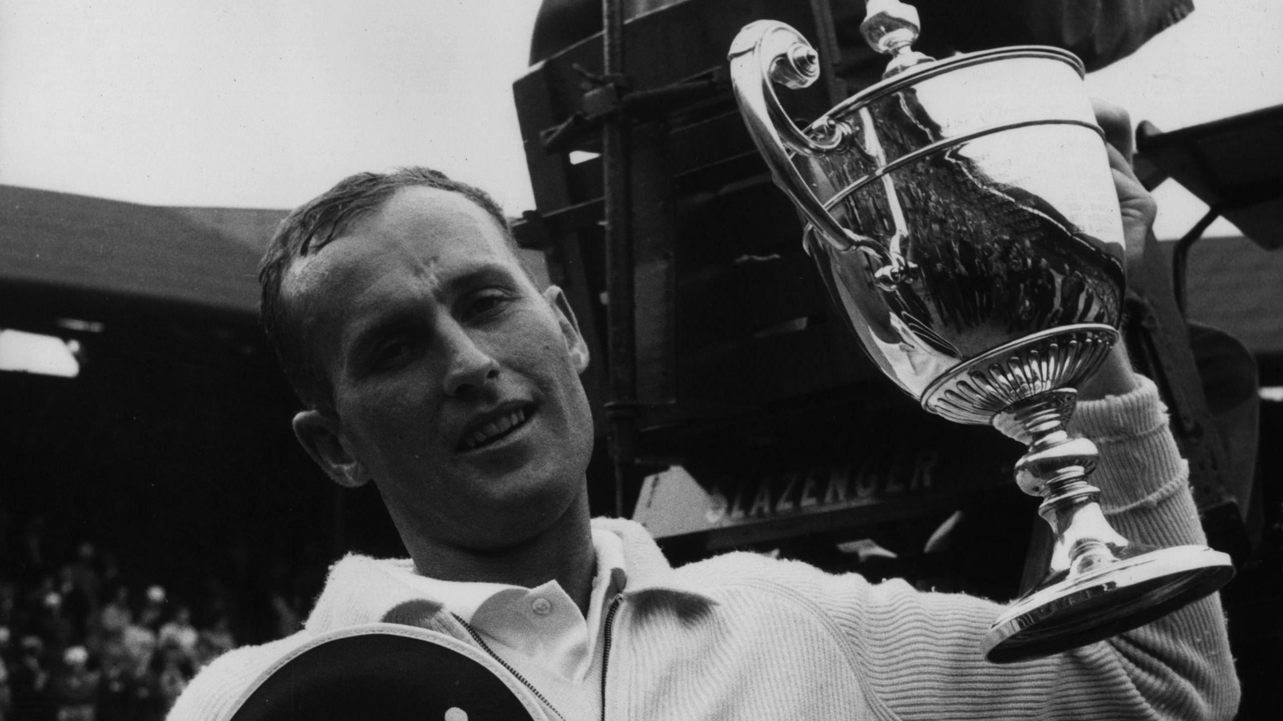 Neale Fraser lifts up the Wimbledon men's singles trophy