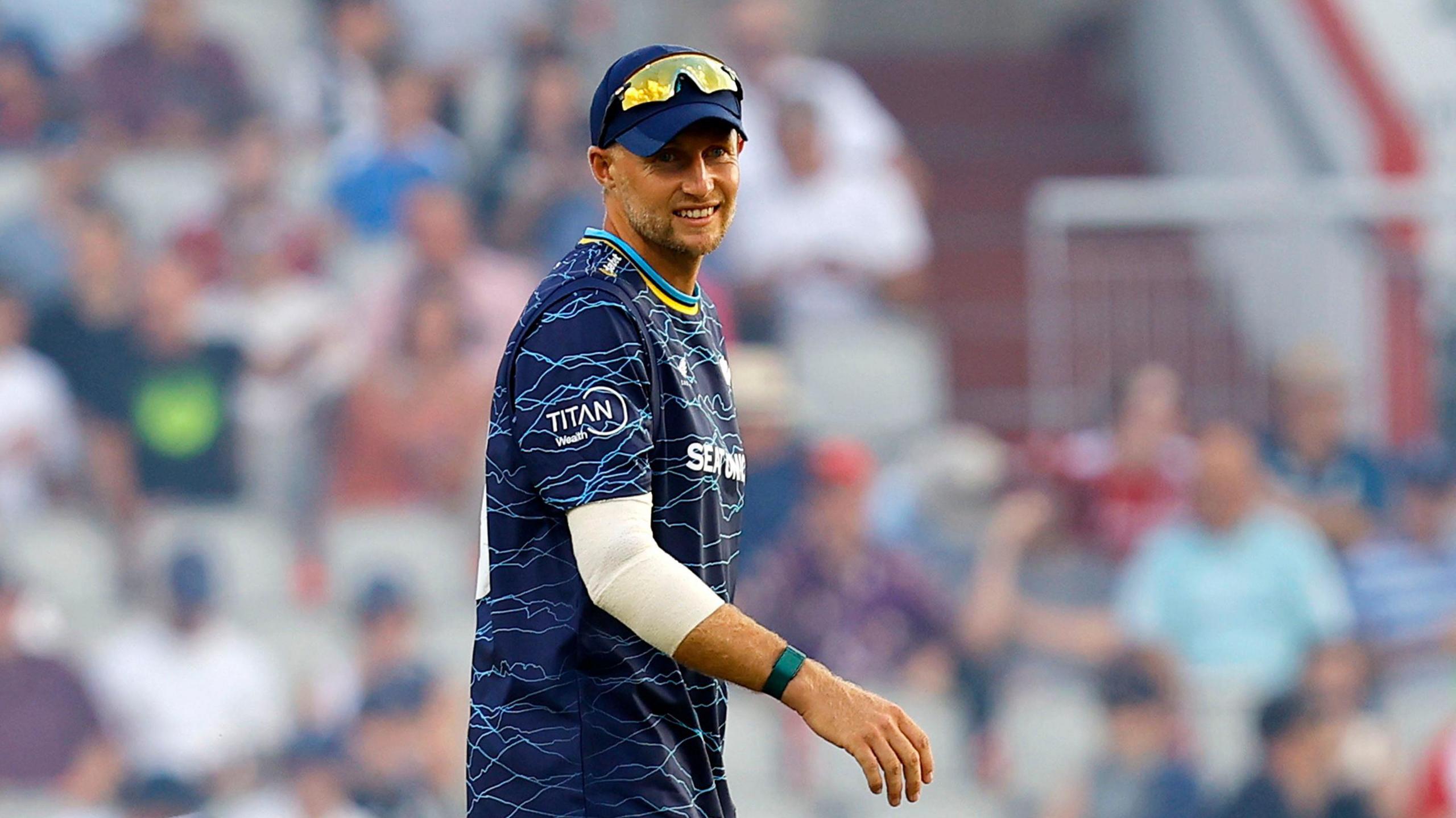 Joe Root in a blue Yorkshire top and cap with sunglasses on his head facing the camera while fielding in a T20 Blast match