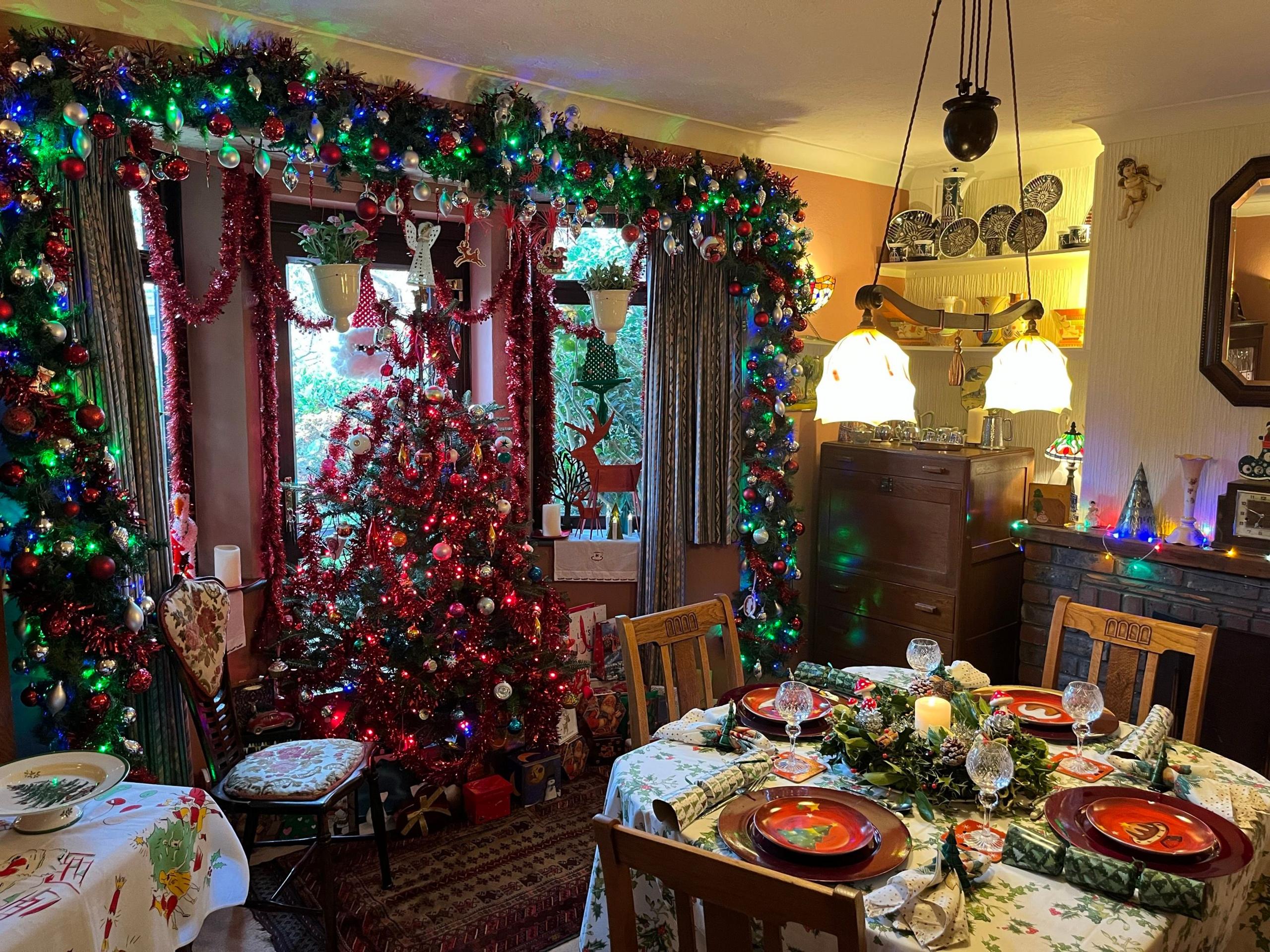 Geoff's dining room which is filled with a big christmas tree, fully laid up table with christmas crackers