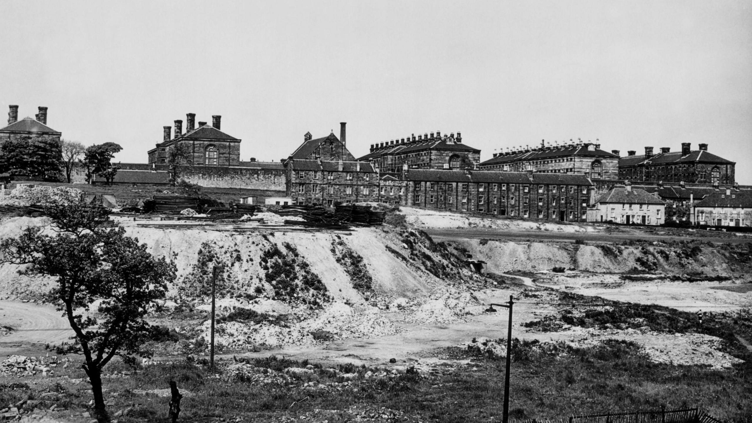 Black and white photo of Victorian prison blocks next to a quarry. 