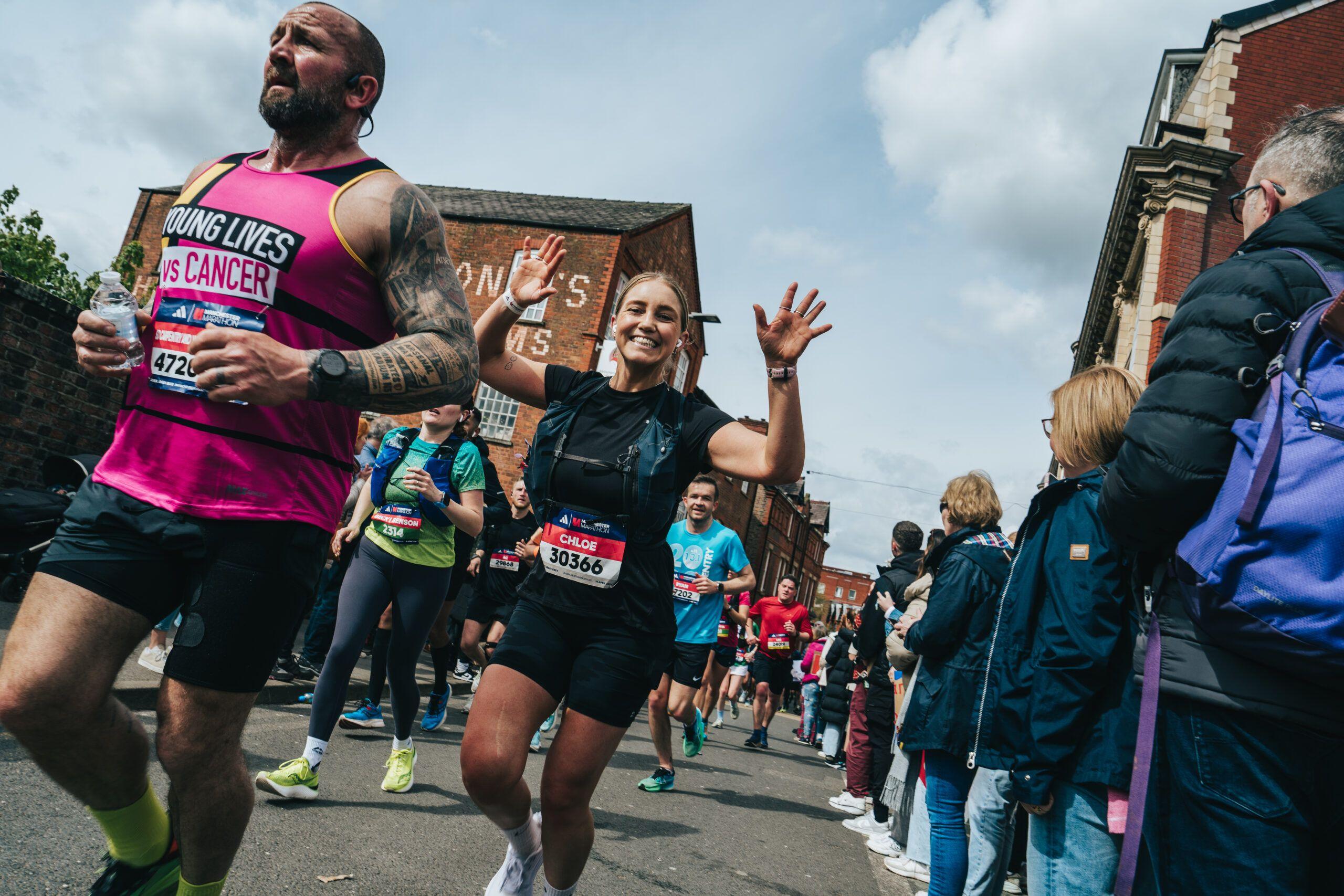 Runner waves during 2024 Manchester Marathon