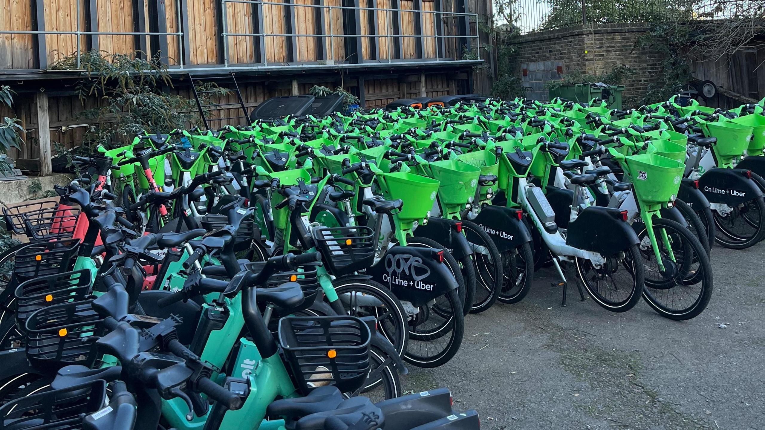 Numerous e-bikes are lined up in a row. Some are from Lime, others are from Bolt.
