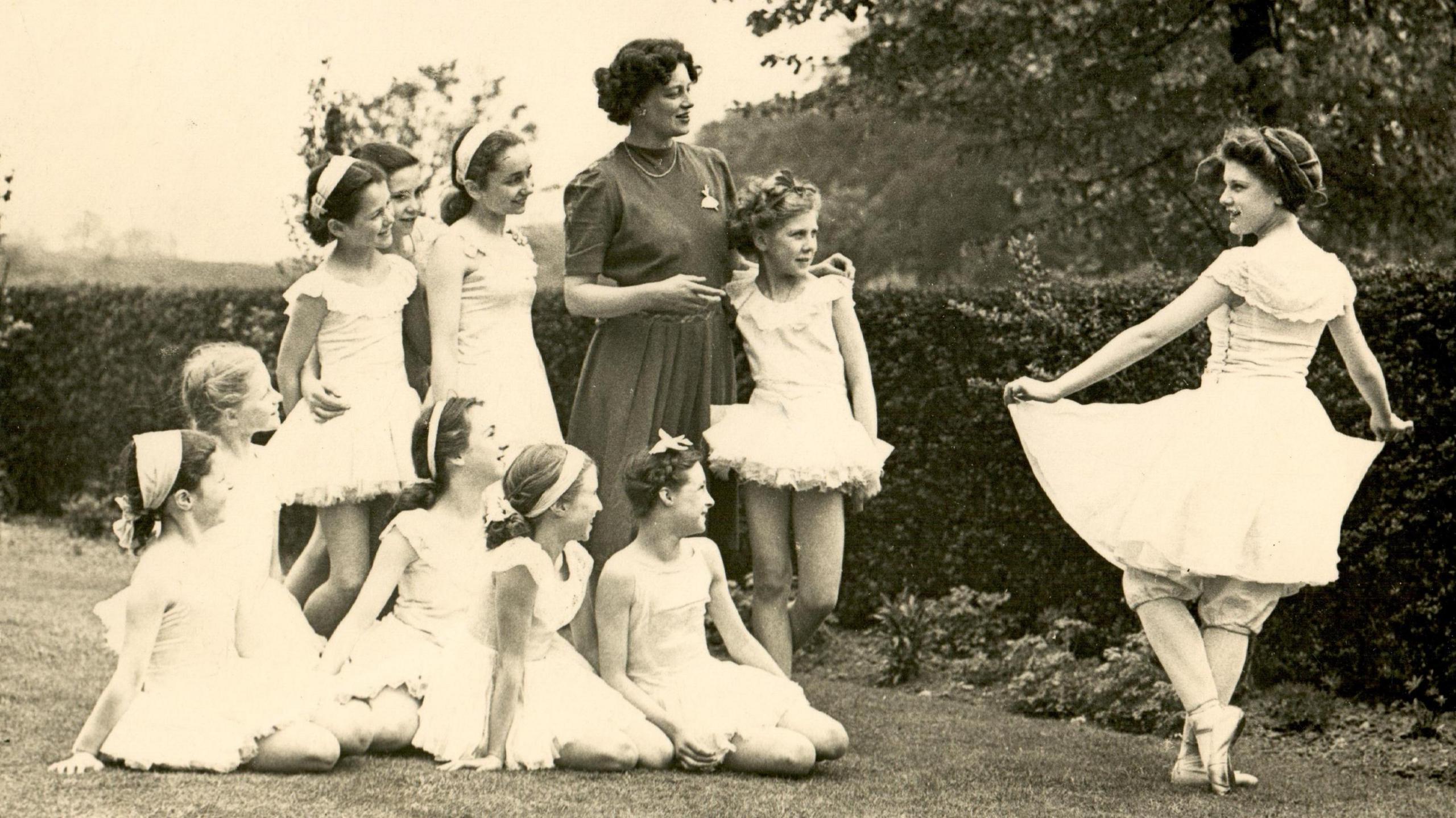 A black and white photo of Sissie Smith with other dance pupils, standing in a garden. 