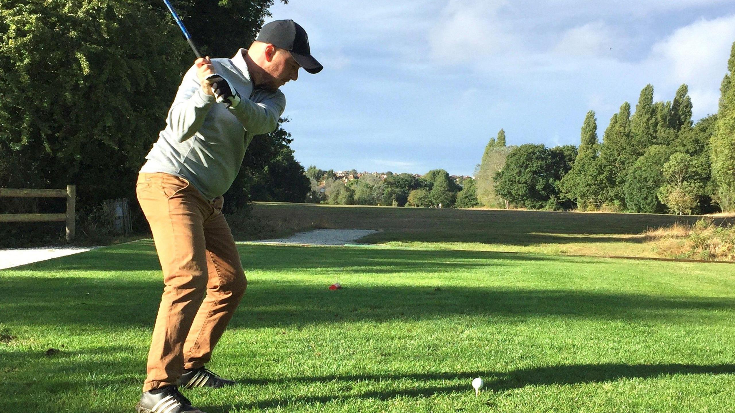 A man teeing off at a gold course