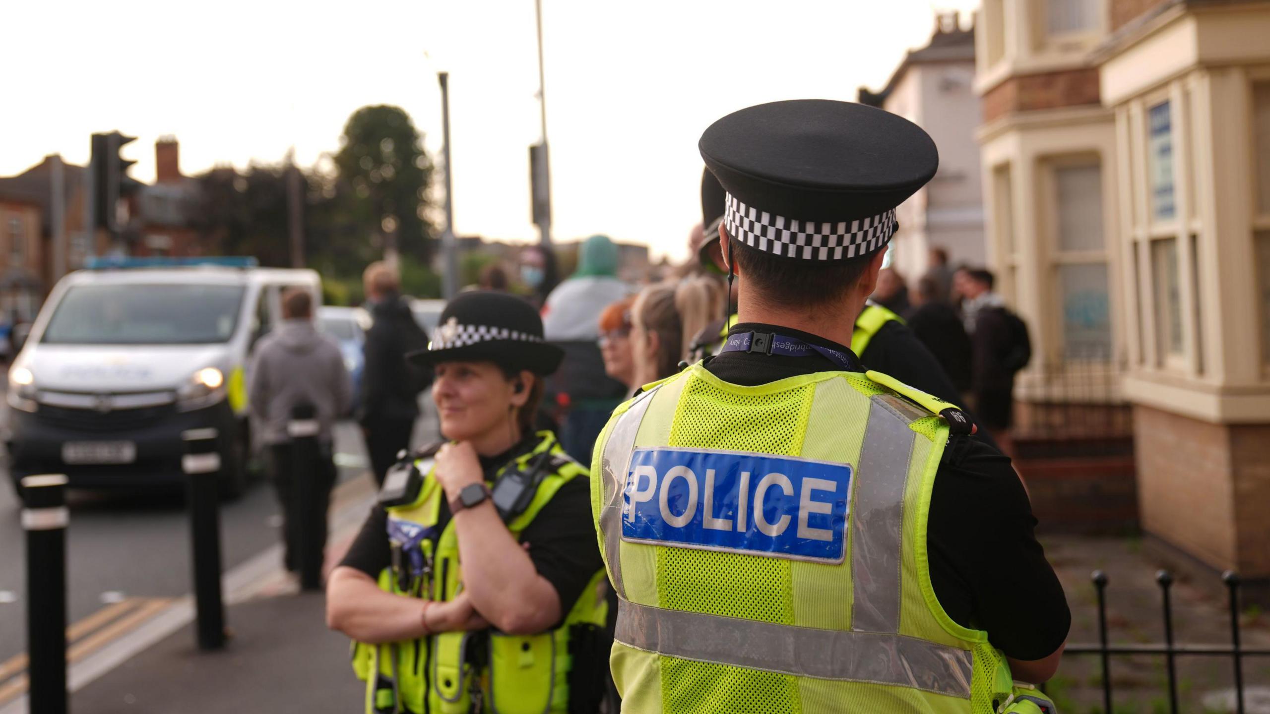 Two police officers stand on a street's pavement 