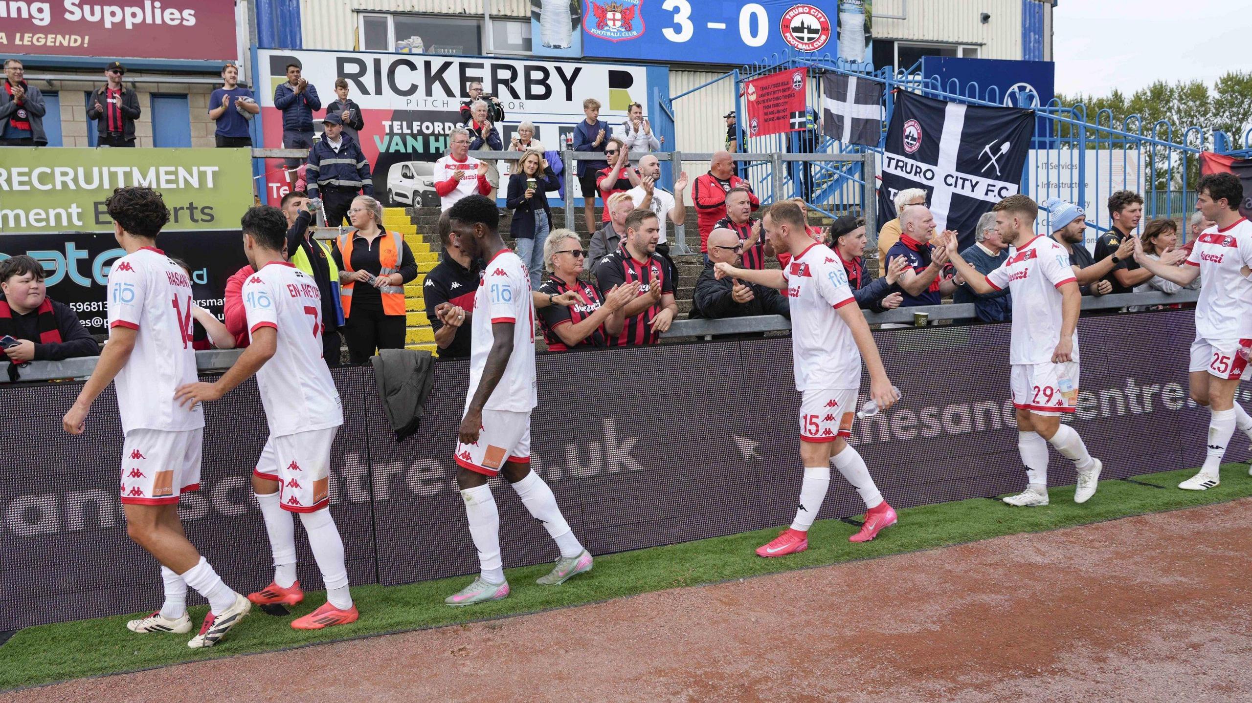 Truro City's players shake hands with fans