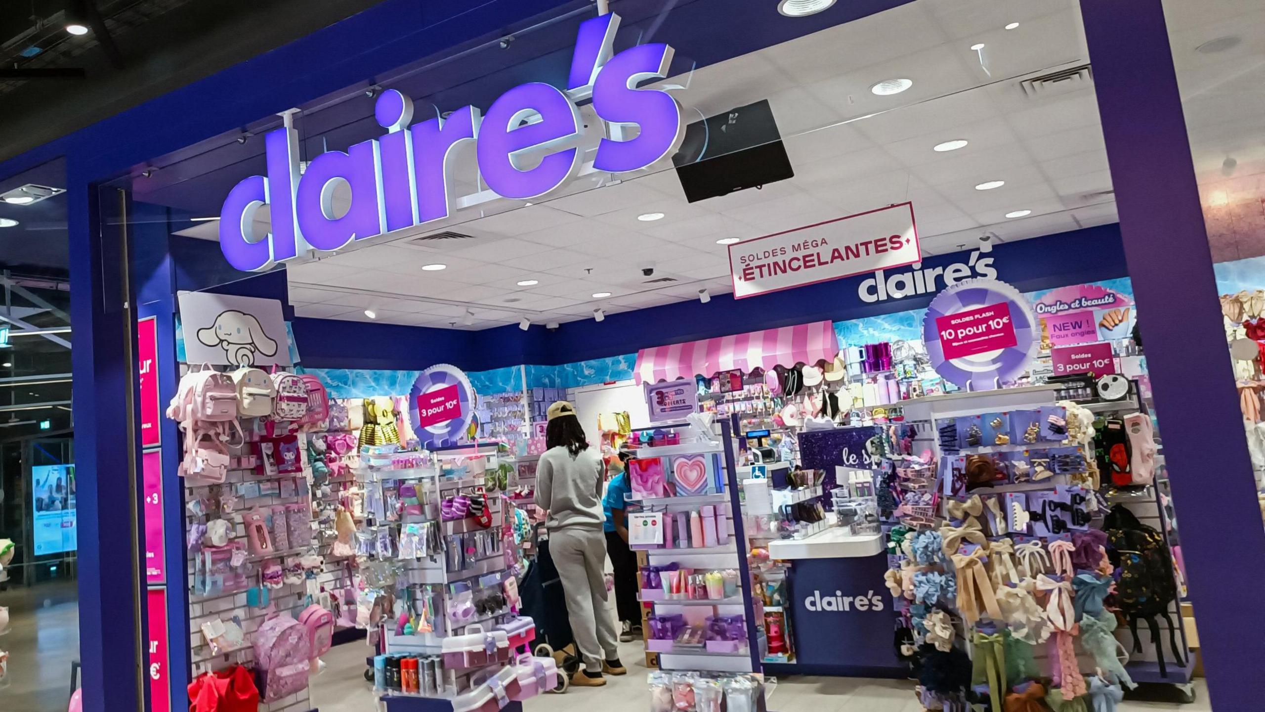 A Claire's store in Paris, with it's purple logo, and array of colourful items inside the store on racks.
