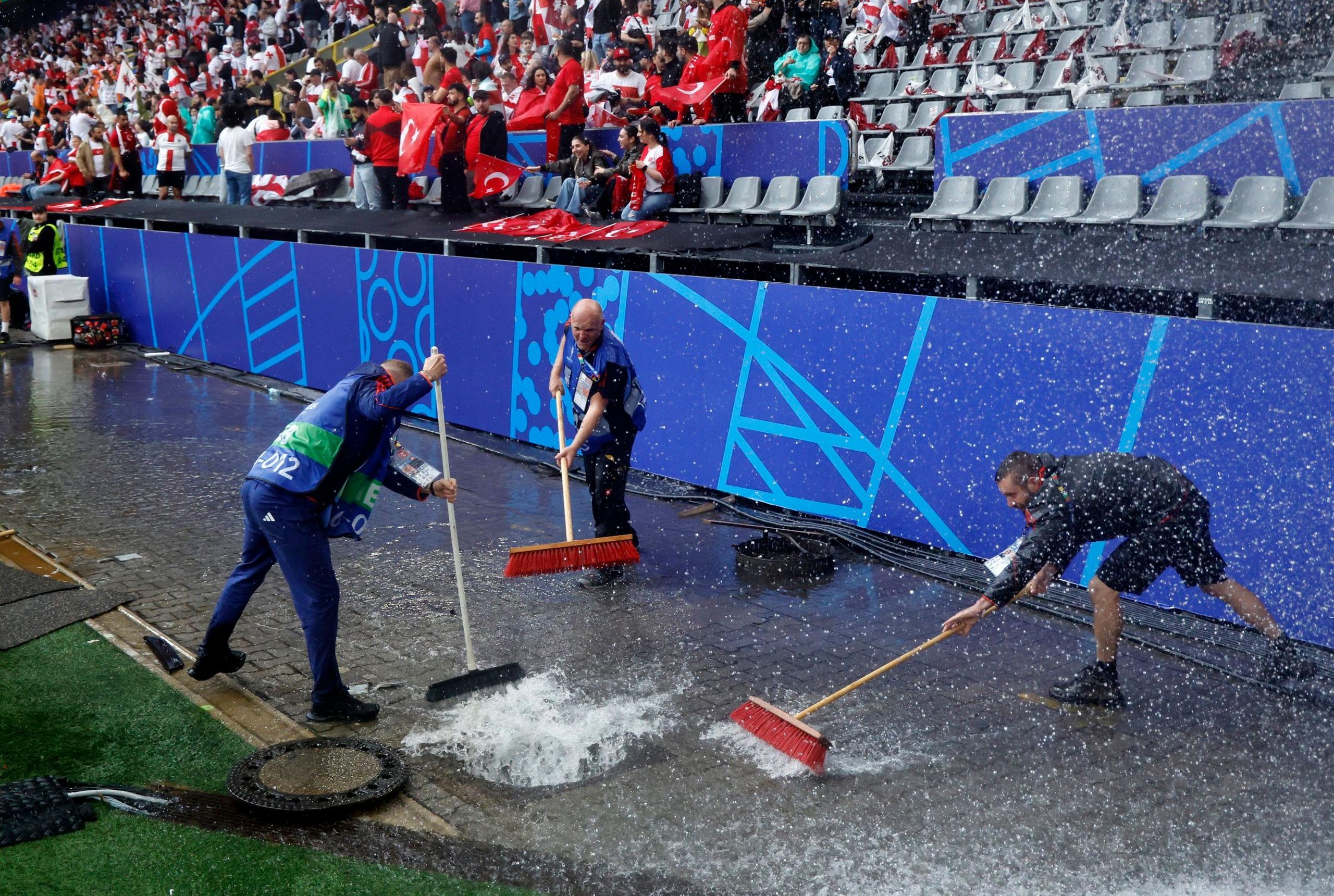 Groundstaff sweep water away after a heavy storm before the Euro 2024 group match between Turkey and Georgia