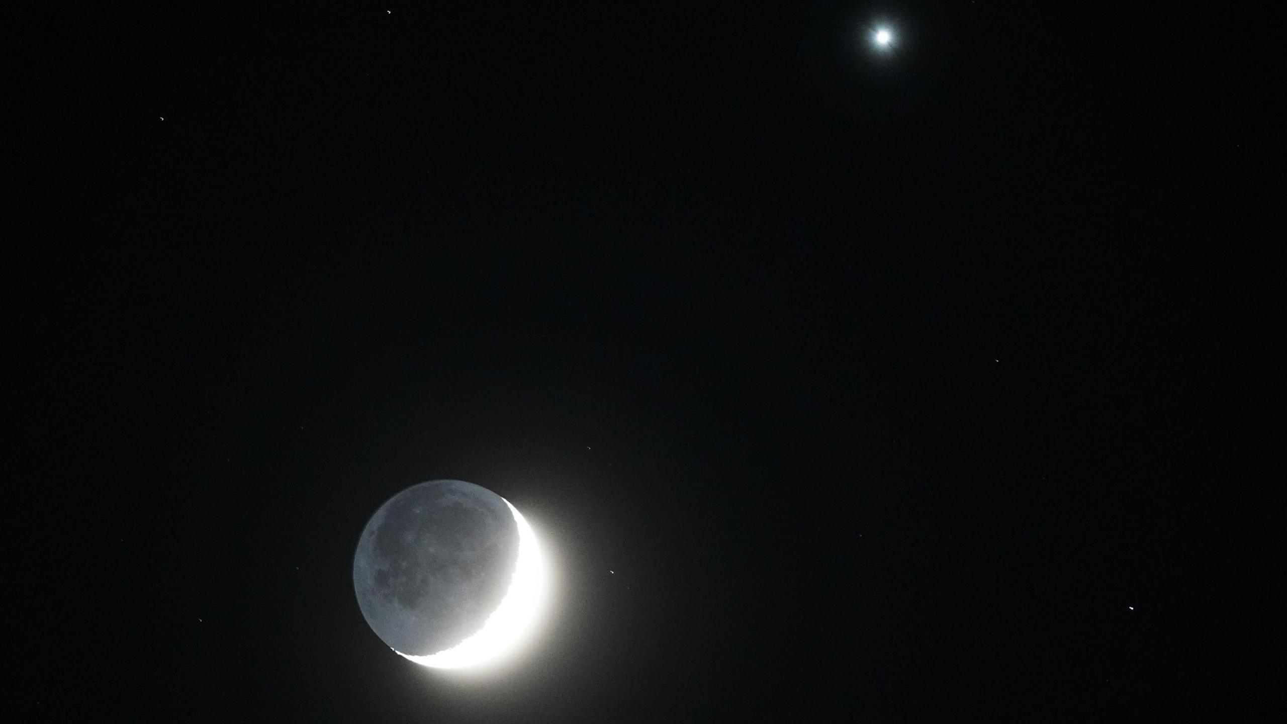 In the UK's Whitley Bay, a shining waxing crescent moon glows with Venus to the right