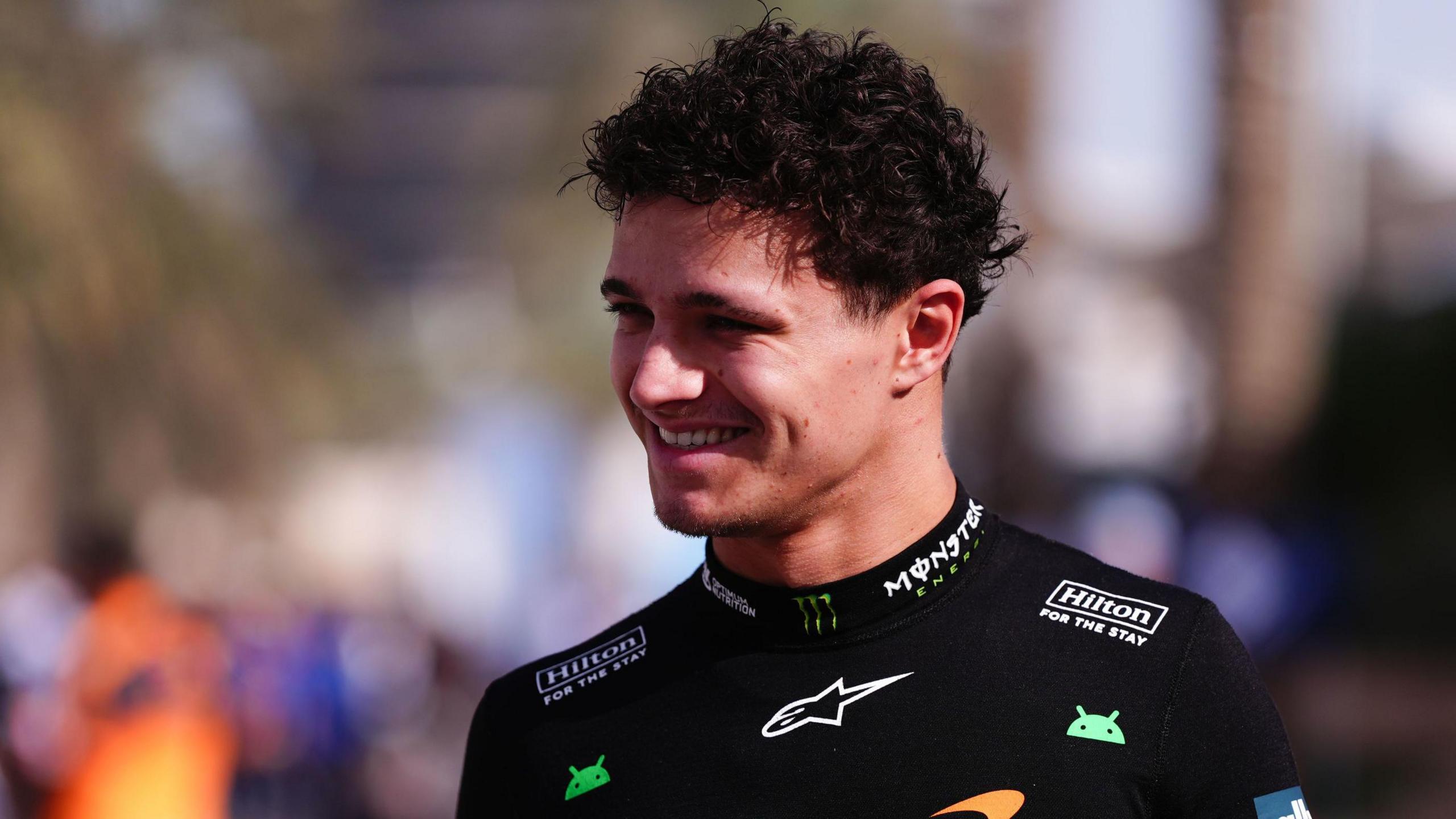 McLaren's Lando Norris smiling in the paddock