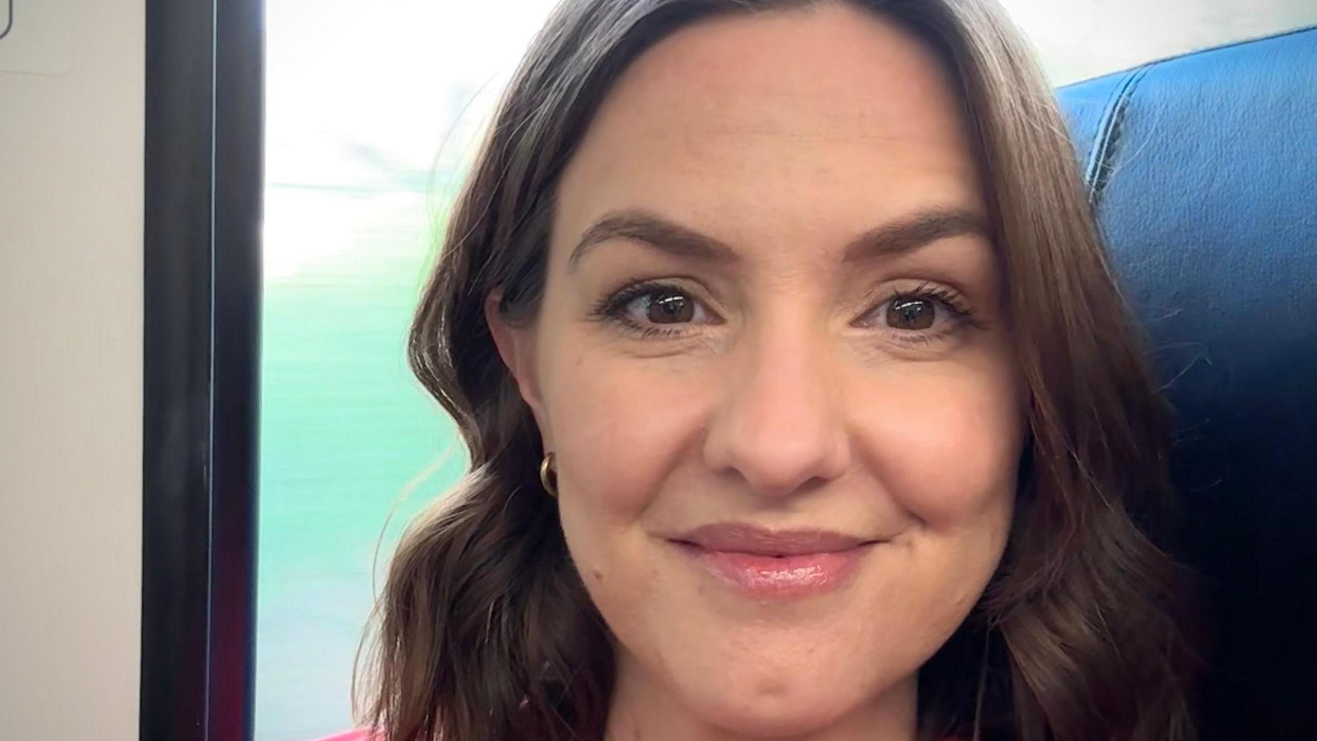 Selfie of Kate Lancaster who has a brown bob hairstyle and is seen smiling on a train