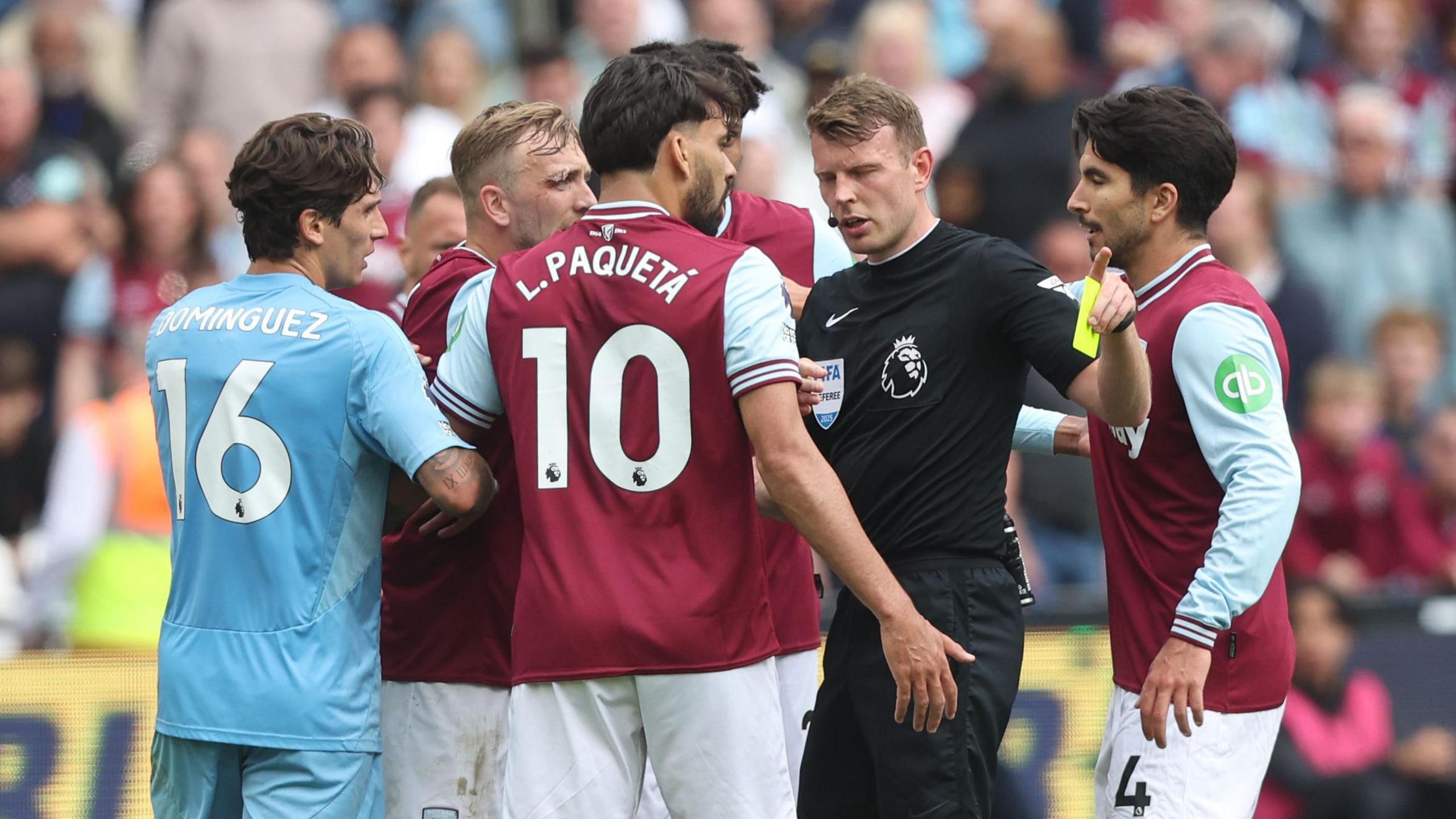 Referee Sam Barrott is surrounded by players from West Ham and Nottingham Forest