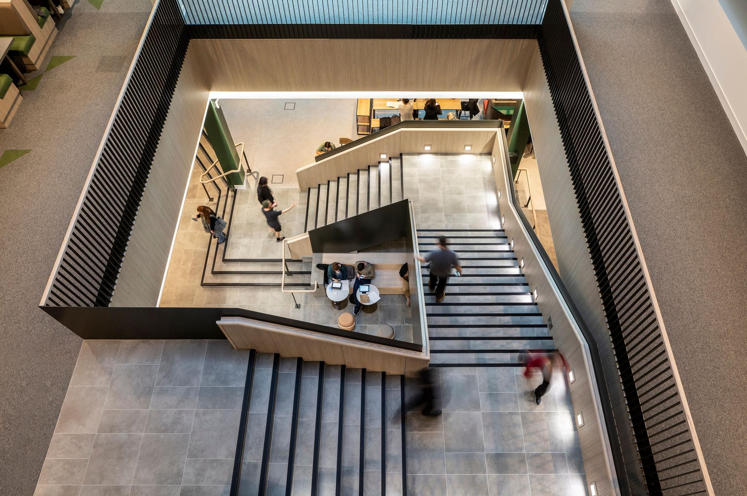 A view from above of a feature stairway, with modern inset lighting, stretching down in a square from a wide landing above giving a feeling of height and space