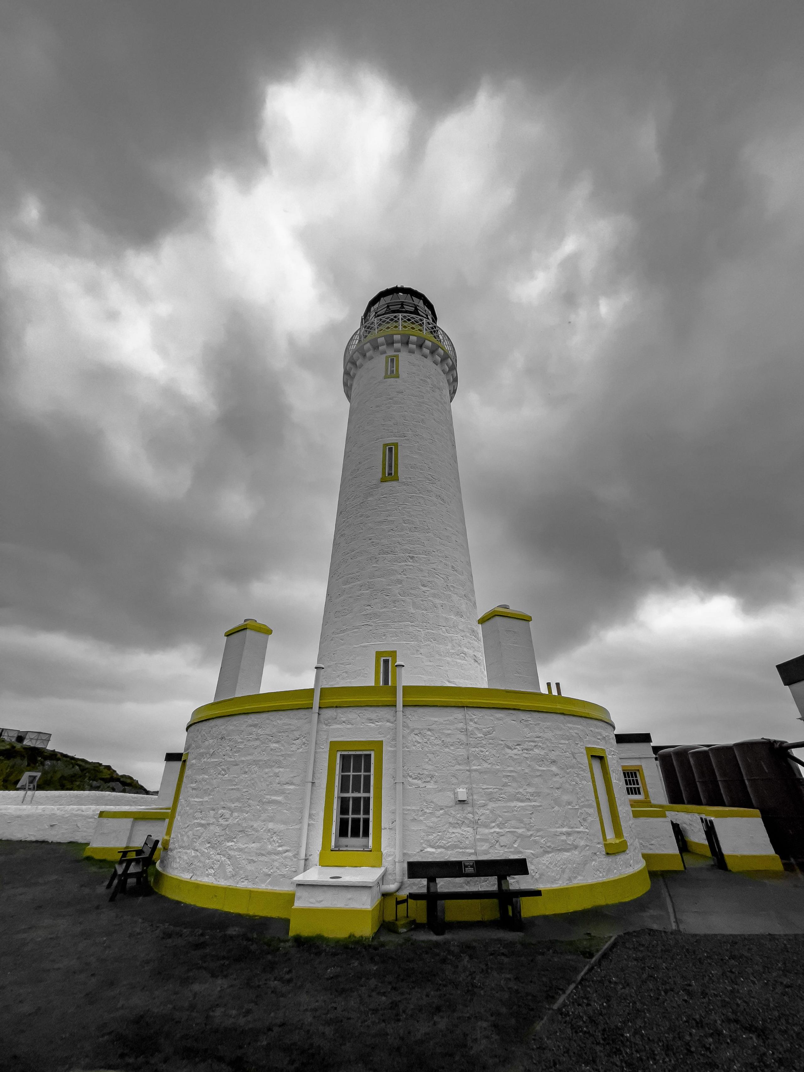 White lighthouse rising in the air with grey clouds overhead