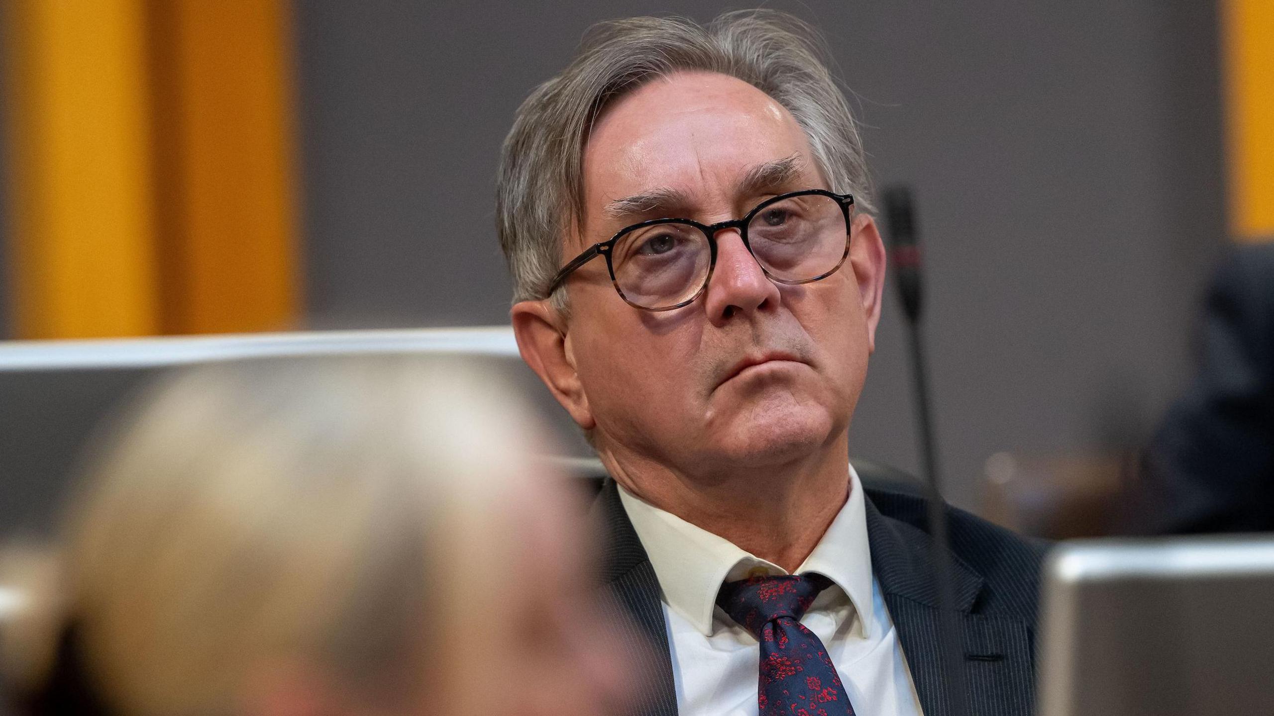 Mick Antoniw sitting in the Senedd chamber with a sombre expression on his face