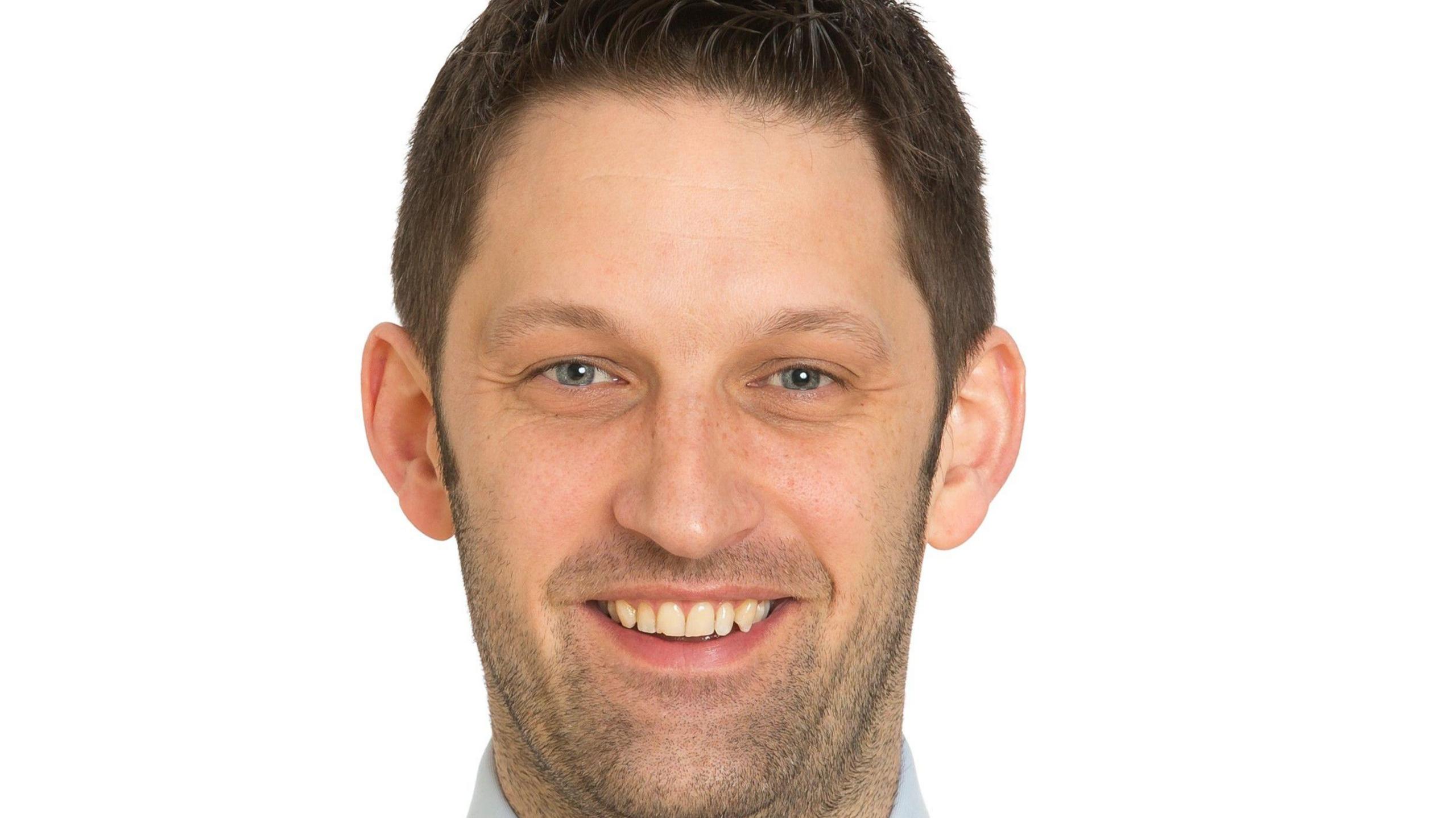 Nick Oswald, headteacher smiles to camera. He's wearing a blue shirt and navy polka dot tie