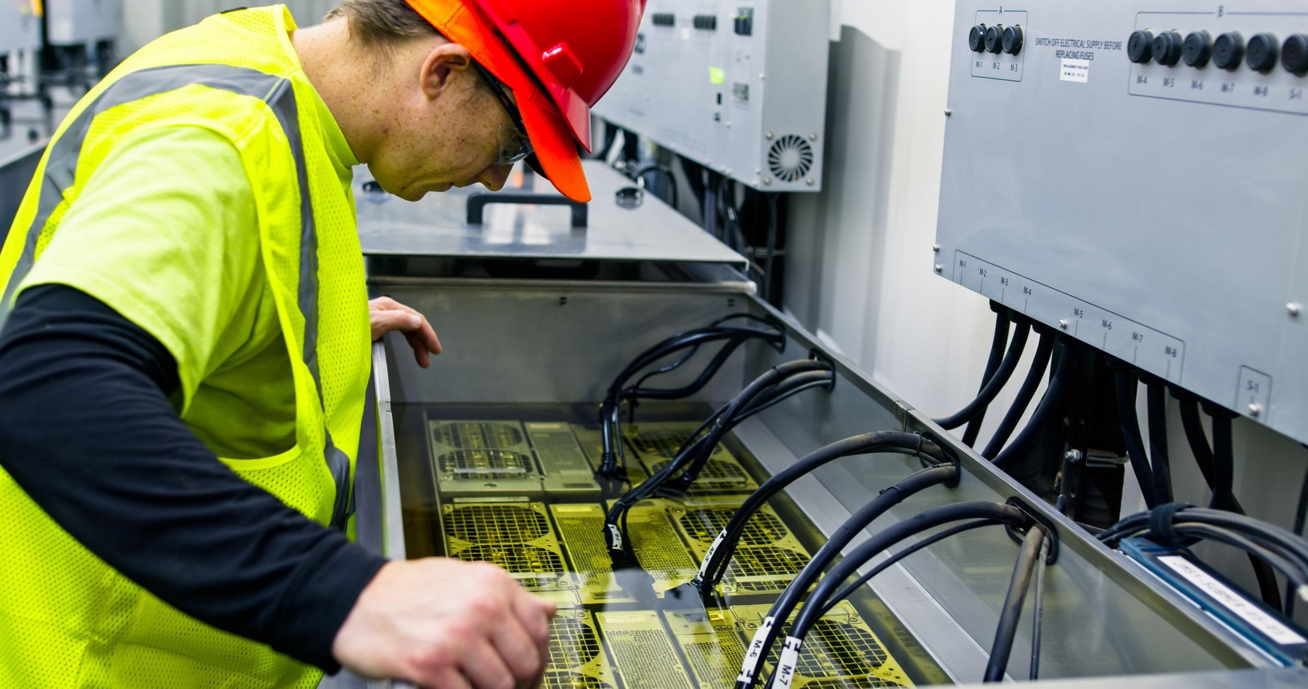 A technician working on an immersion cooling system in a data center for cryptocurrency mining, cloud services and AI computing