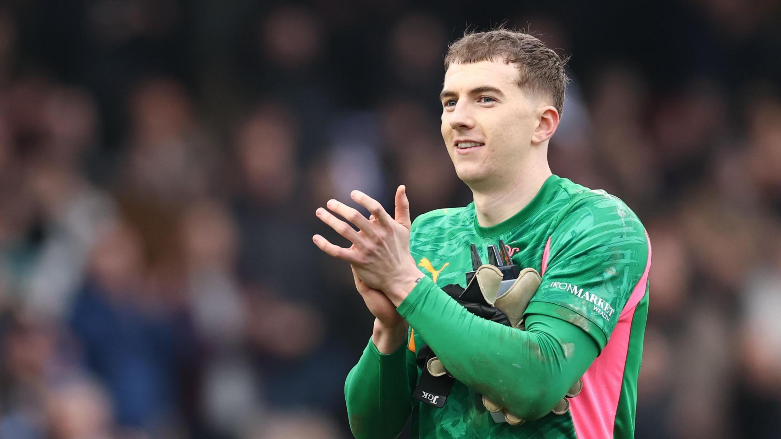 Port Vale goalkeeper Joe Gauci claps the crowd after a game with his gloves tucked underneath his arms