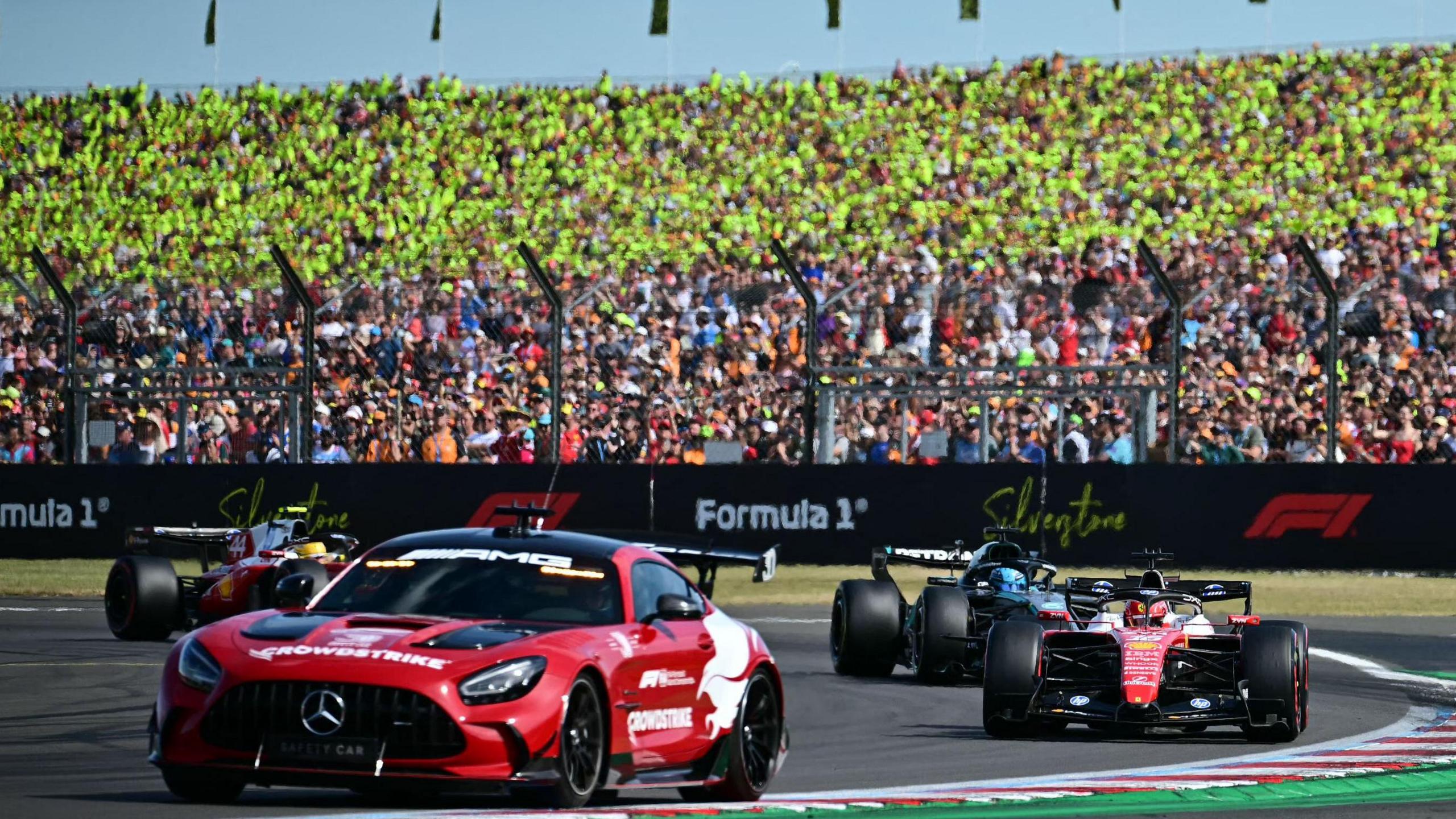 The safety car leads the field around Silverstone with race winner Charles Leclerc following immediately behind in his Ferrari