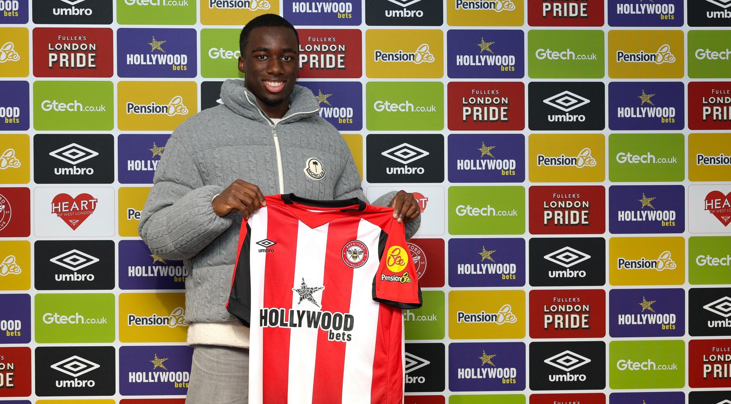 Michael Kayode poses with a Brentford shirt