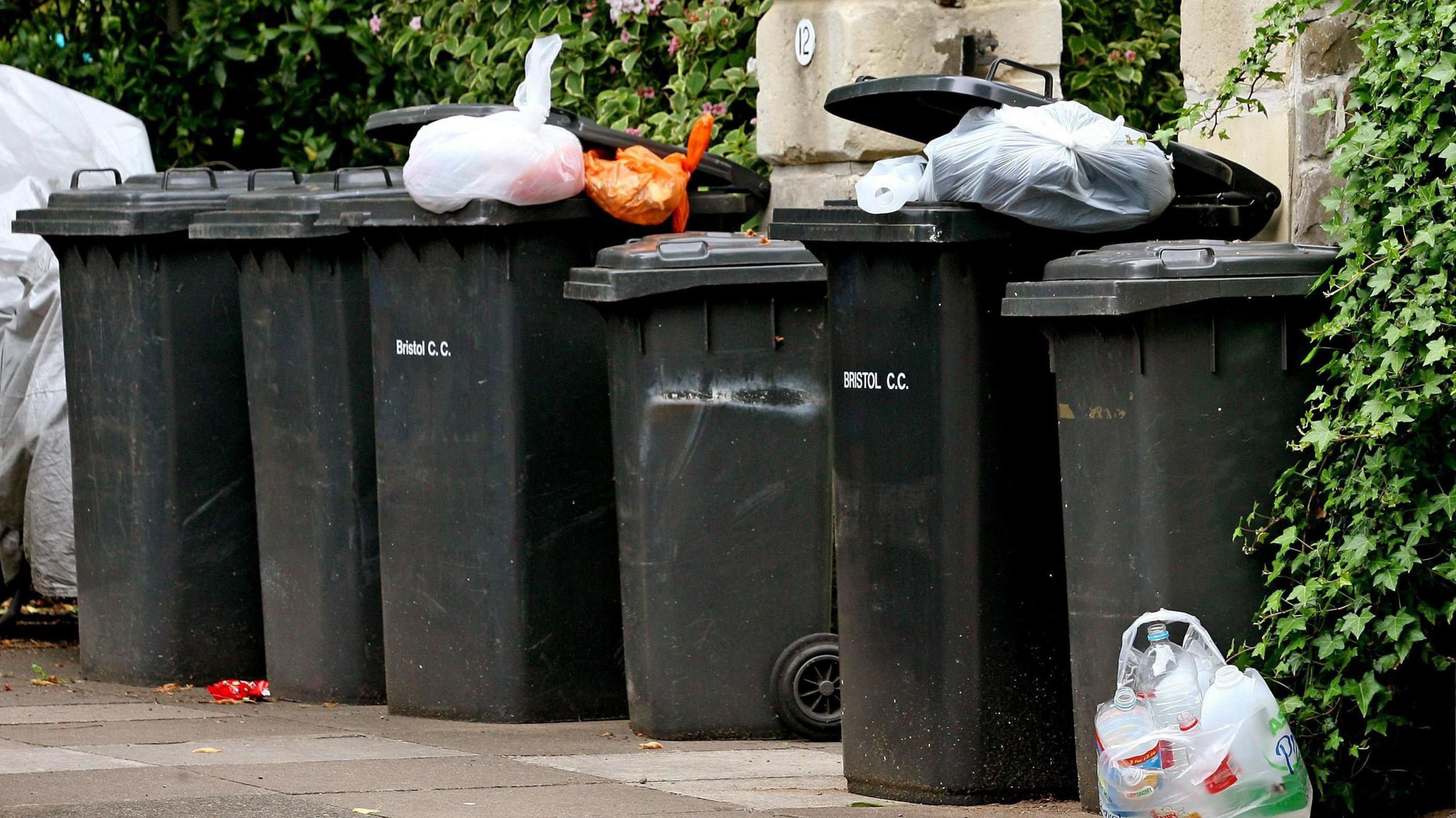 Household wheelie bins wait to be emptied on a street in Bristol.