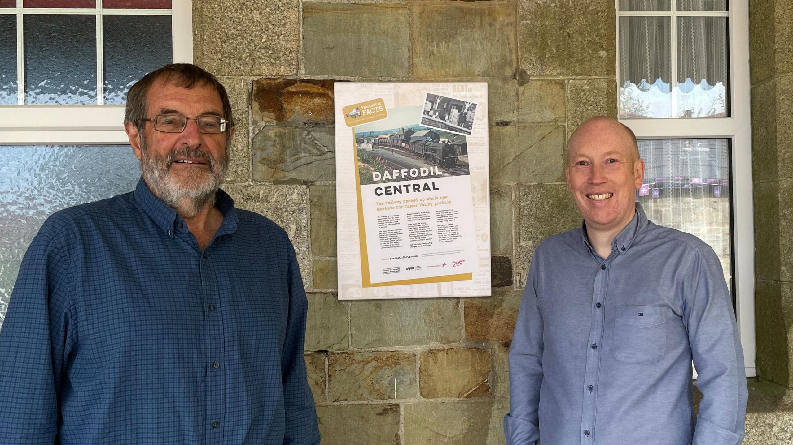 Historian Clive Charlton (left) and Mike Parker-Bray (right) from the Devon and Cornwall Rail Partnership stand either side of one the of new information panels. This one tells the story of how the railway caused a boom for the flower growing industry in the Tamar valley.