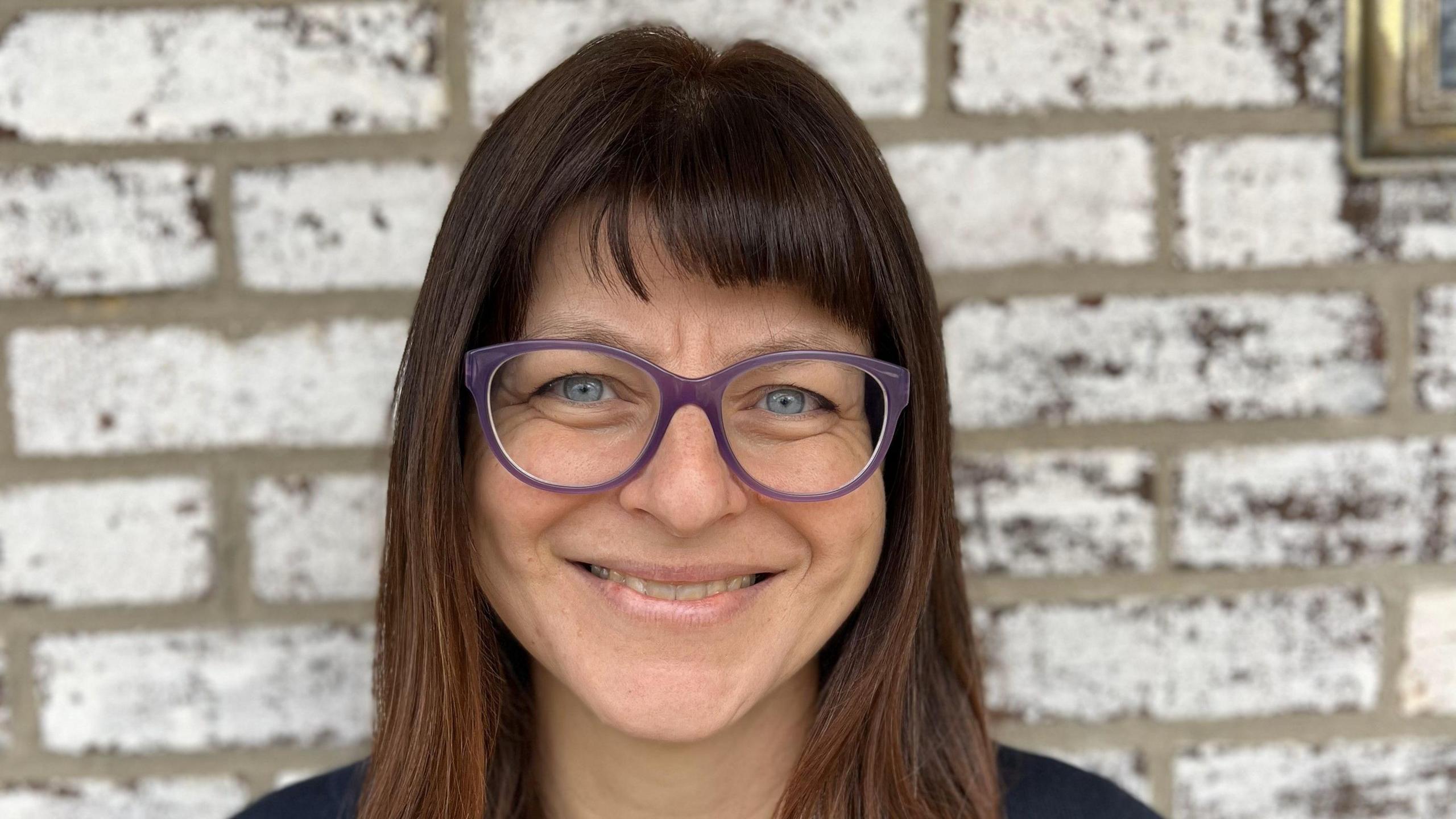 Dr Ylenia Chiari, looking at the camera, stood in front of a wall