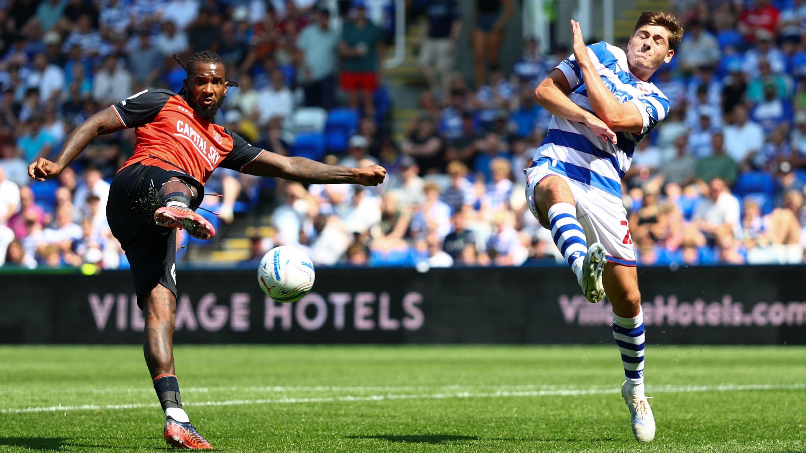 Kasey Palmer of Luton fires the ball towards goal as a Reading defender tries to block the shot.