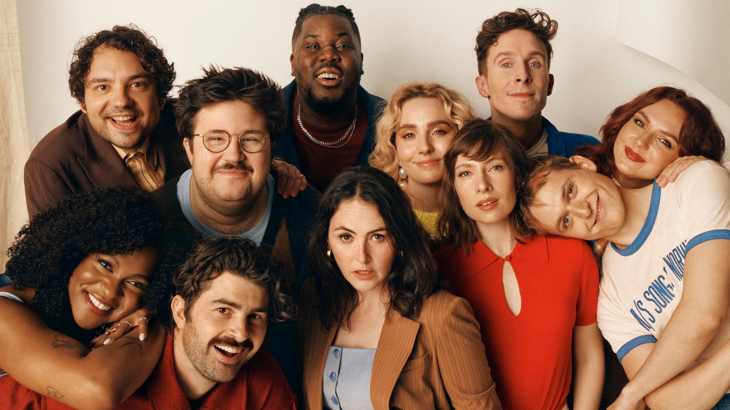 Group photo of the diverse 11-member SNL UK cast posing confidently in a studio setting, showcasing their energetic and comedic personalities.