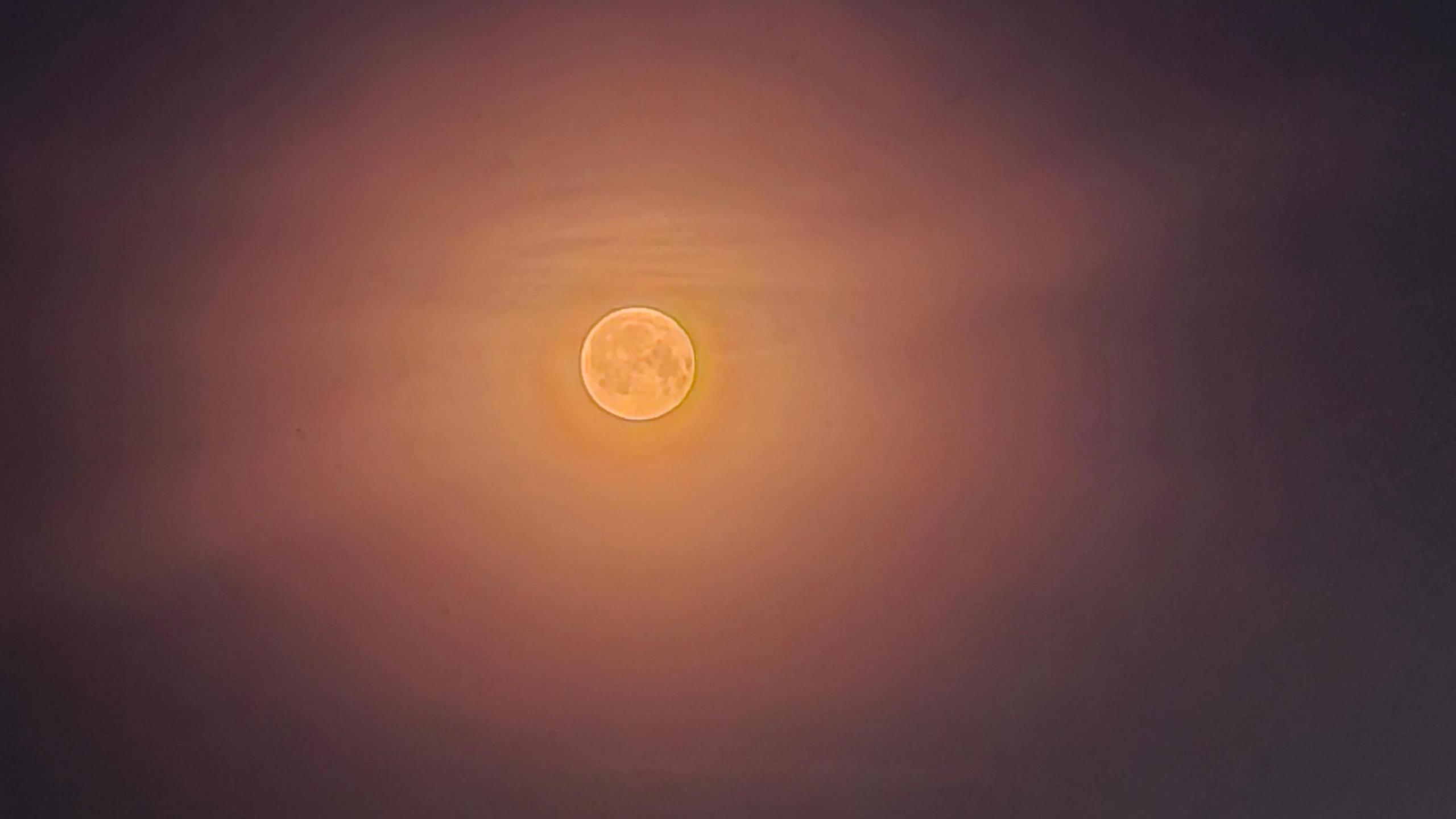 A blurry view of an orange-coloured moon. 