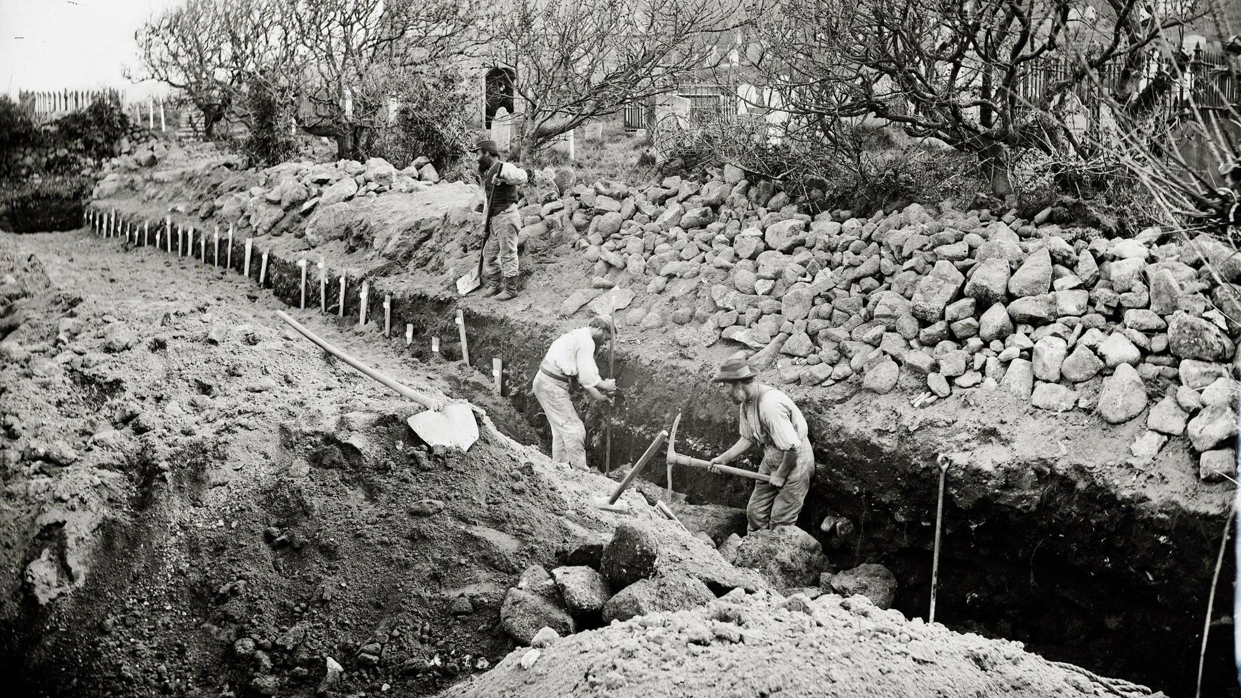 A Victorian era picture shows a group of men digging a large grave with pickaxes. It's in the St Mary's Old Town Church on The Isles of Scilly