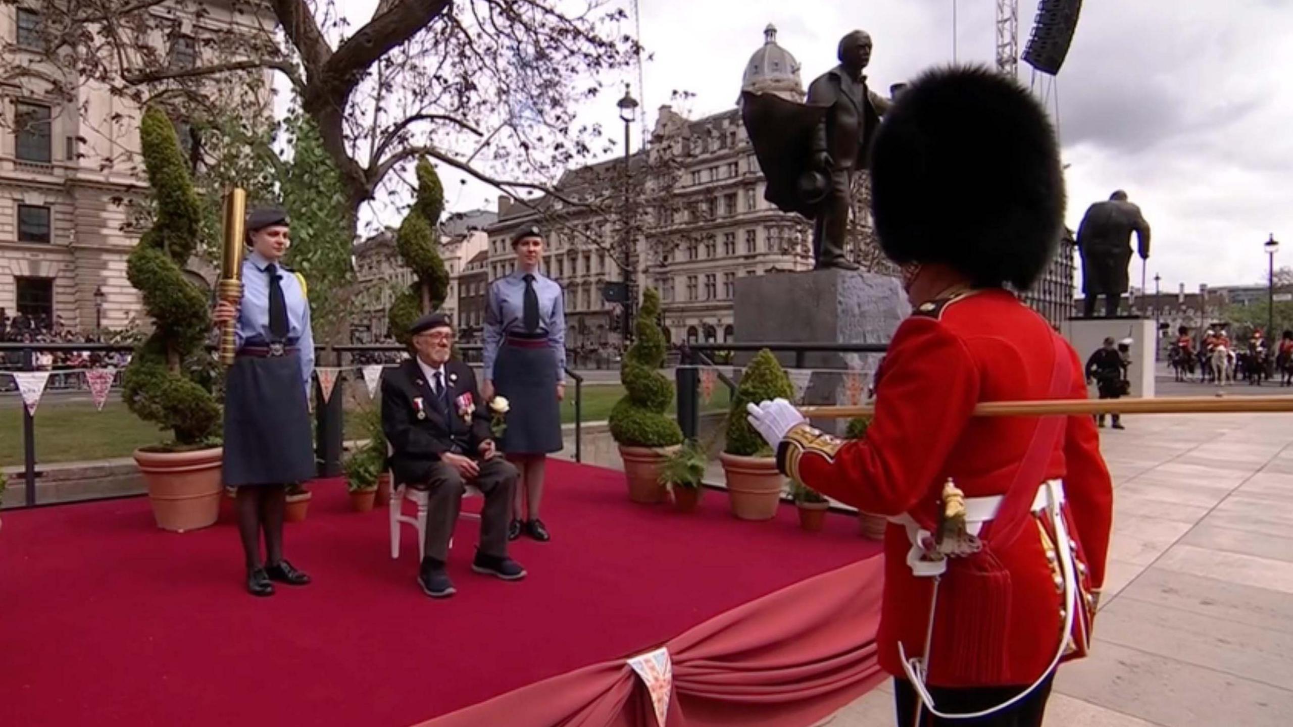 Alan Kennett sitting down starting the VE parade in London. Two RAF cadets are beside him and in front of him is a member of the King's Guard.