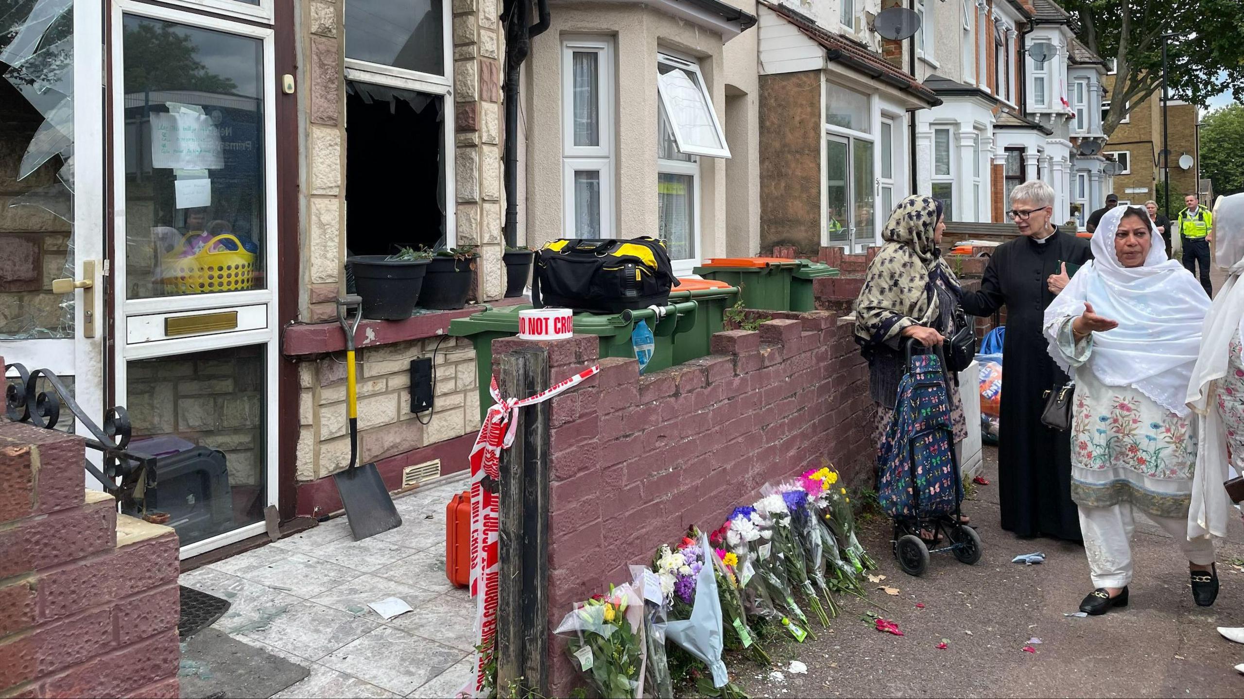 Flowers left outside the house as members of the community stand outside