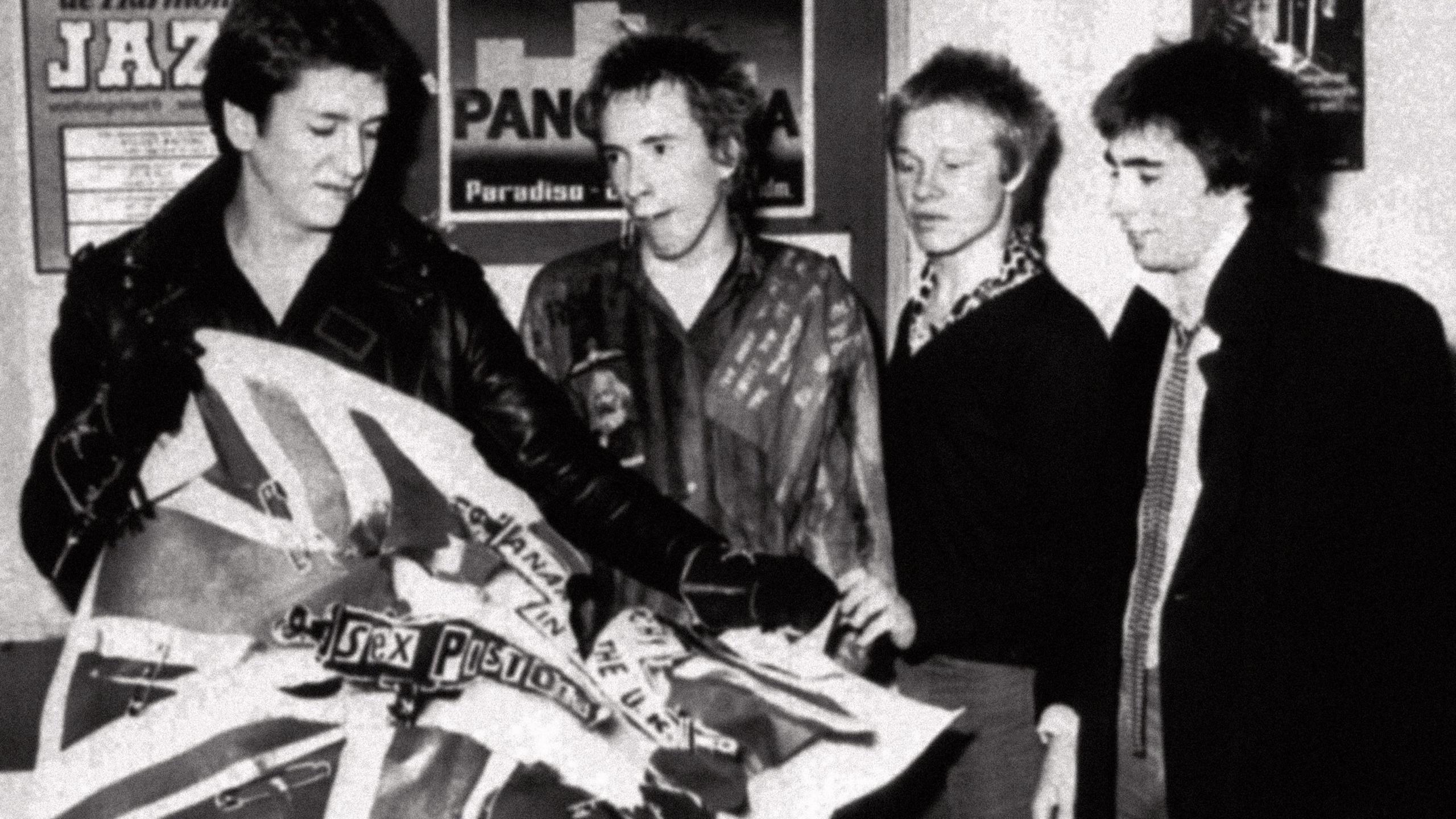 The Sex Pistols - left to right, Steve Jones, Johnny Rotten, Paul Cook and Glen Matlock - after the announcement that they have split with their record company EMI in 1977. Steve Jones, the guitarist, is tearing up a poster for their first single, Anarchy in the UK, which was released on EMI