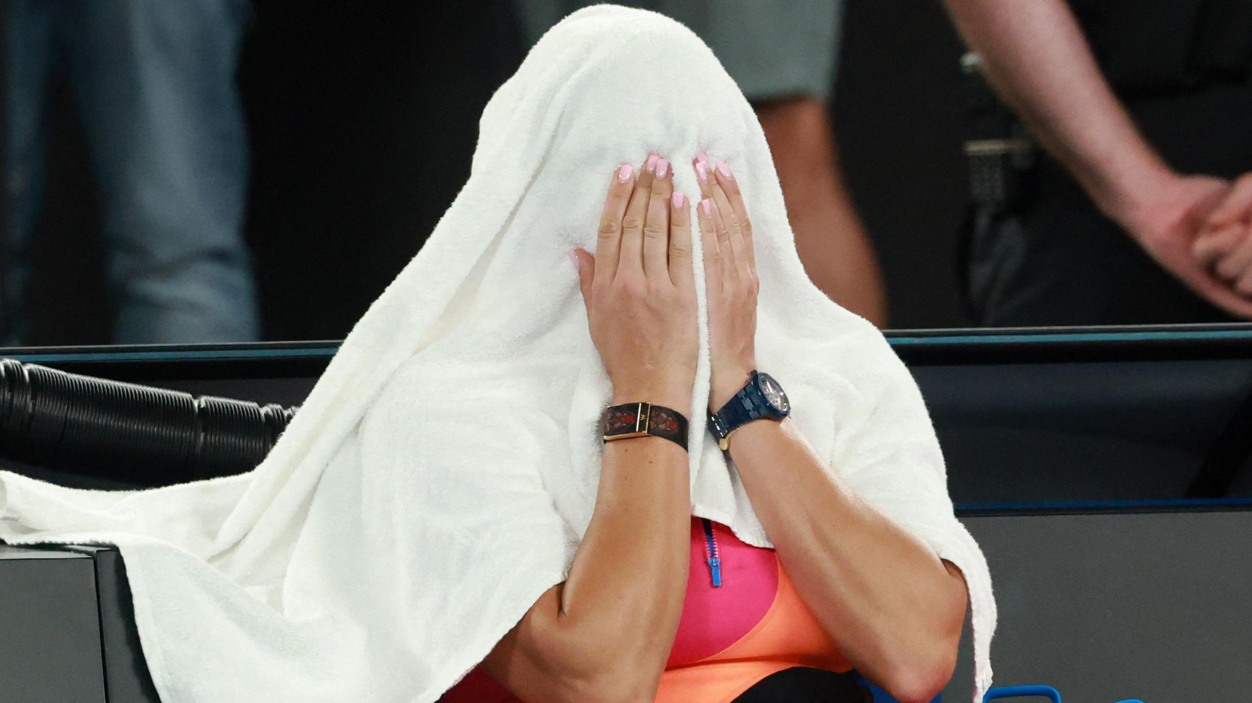 Aryna Sabalenka covers her head with a towel