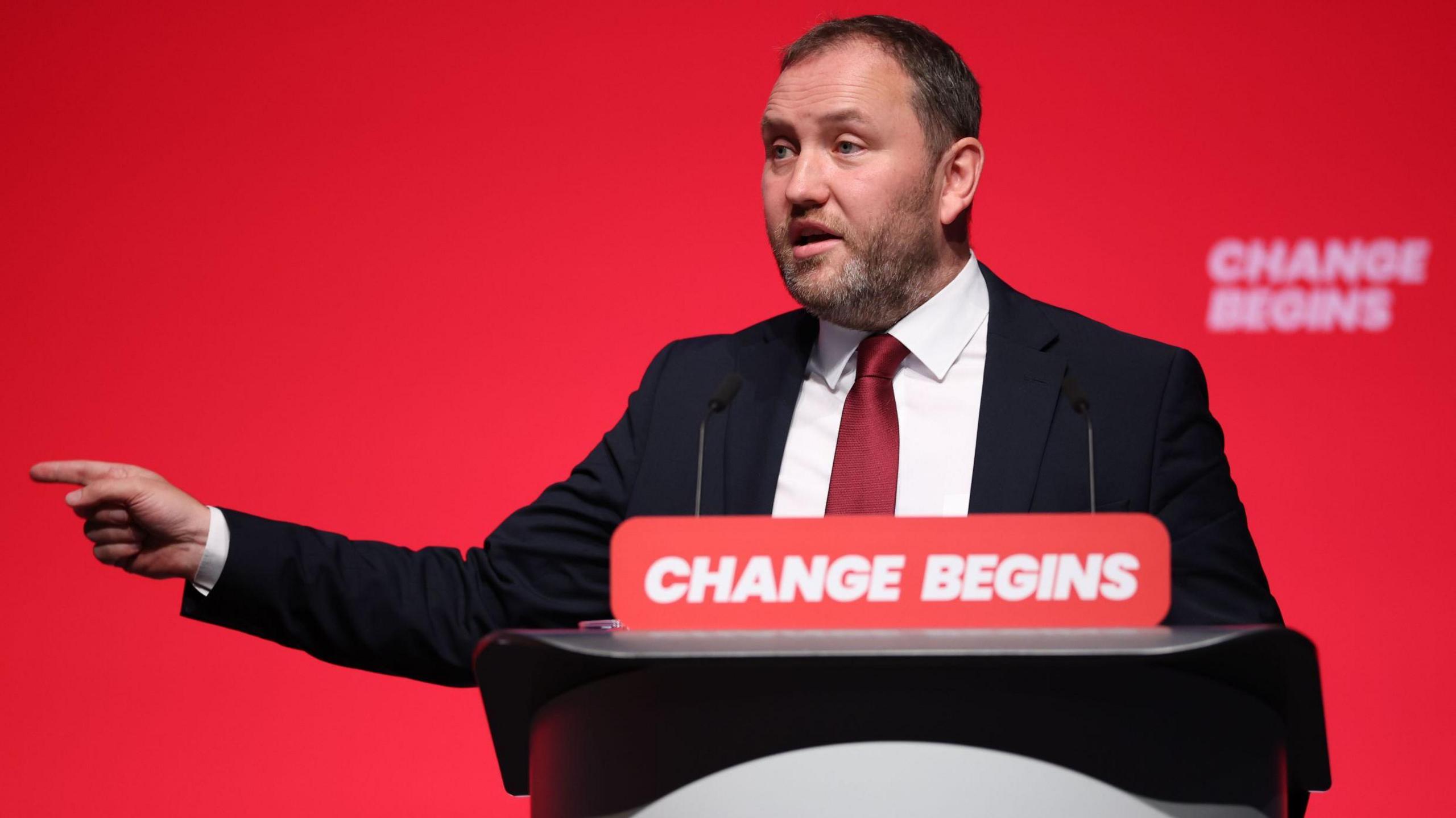 Ian Murray, dressed in a suit, speaking at the Labour party conference. He is pointing off camera.