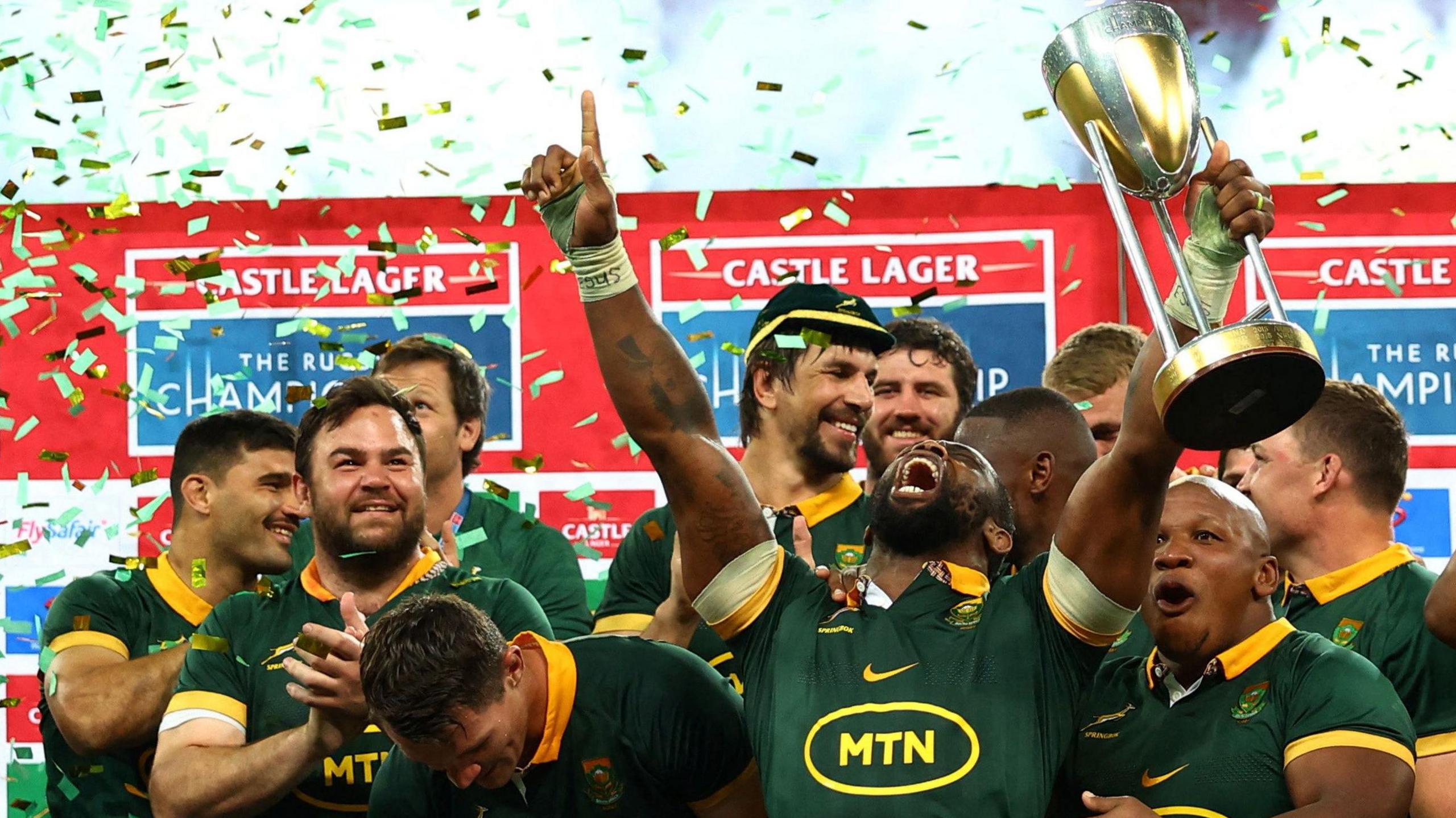 Siya Kolisi lifts the Rugby Championship trophy and screams into the air as other South Africa players look on in admiration