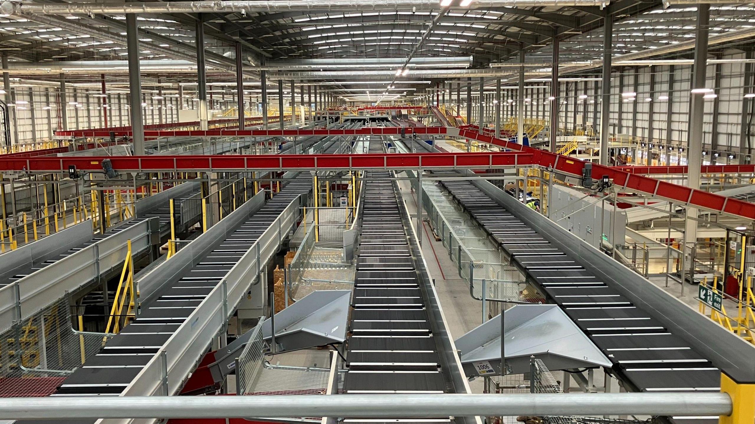 A vast warehouse that processes parcels. Conveyor belts stretch from one end of the warehouse to the other.