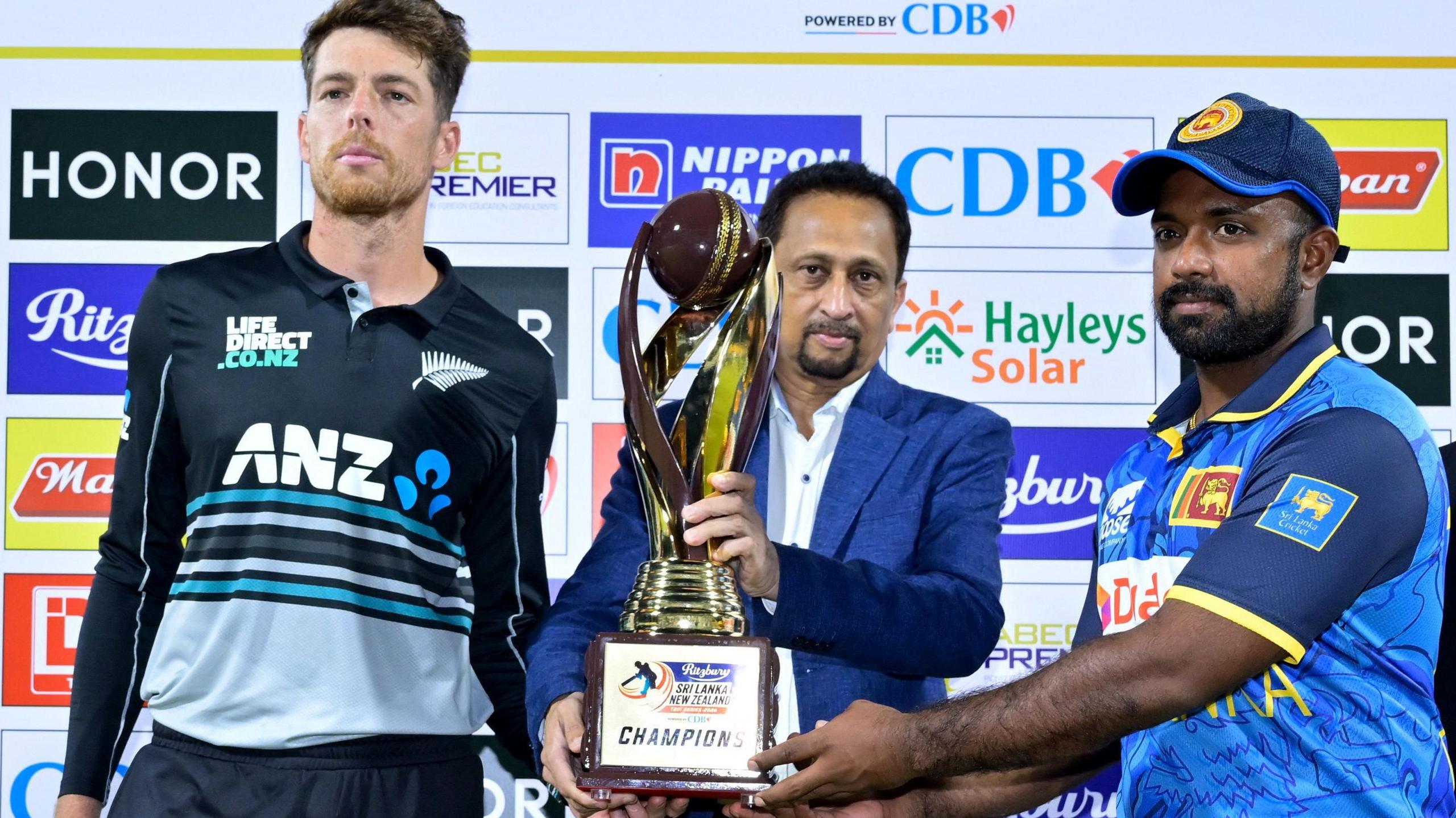 New Zealand captain Mitchell Santner and Sri Lanka skipper Charith Asalanka with the T20 series trophy