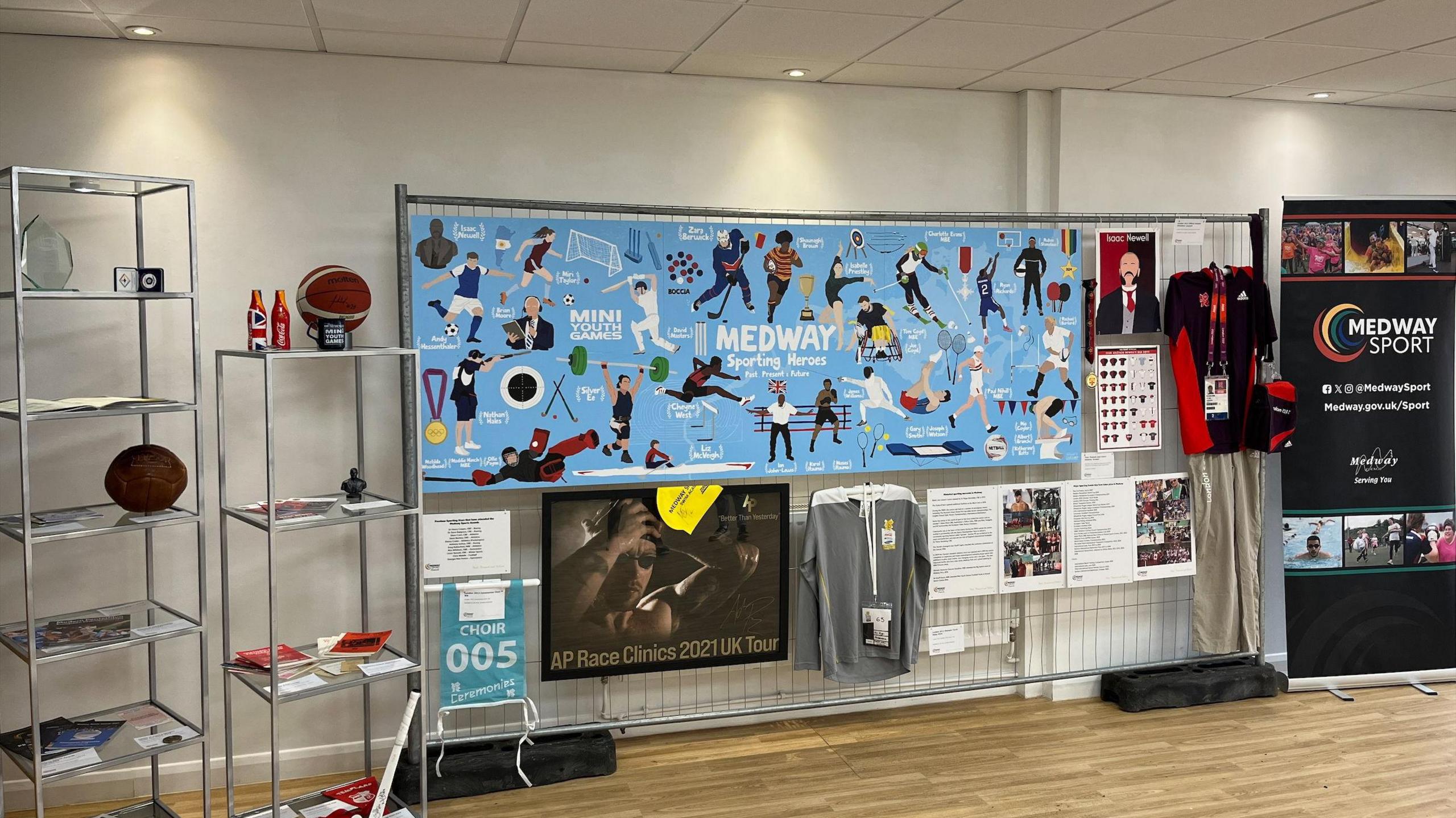 Artefacts, including a basket ball, a rugby ball and a cricket strip, are displayed in a museum.