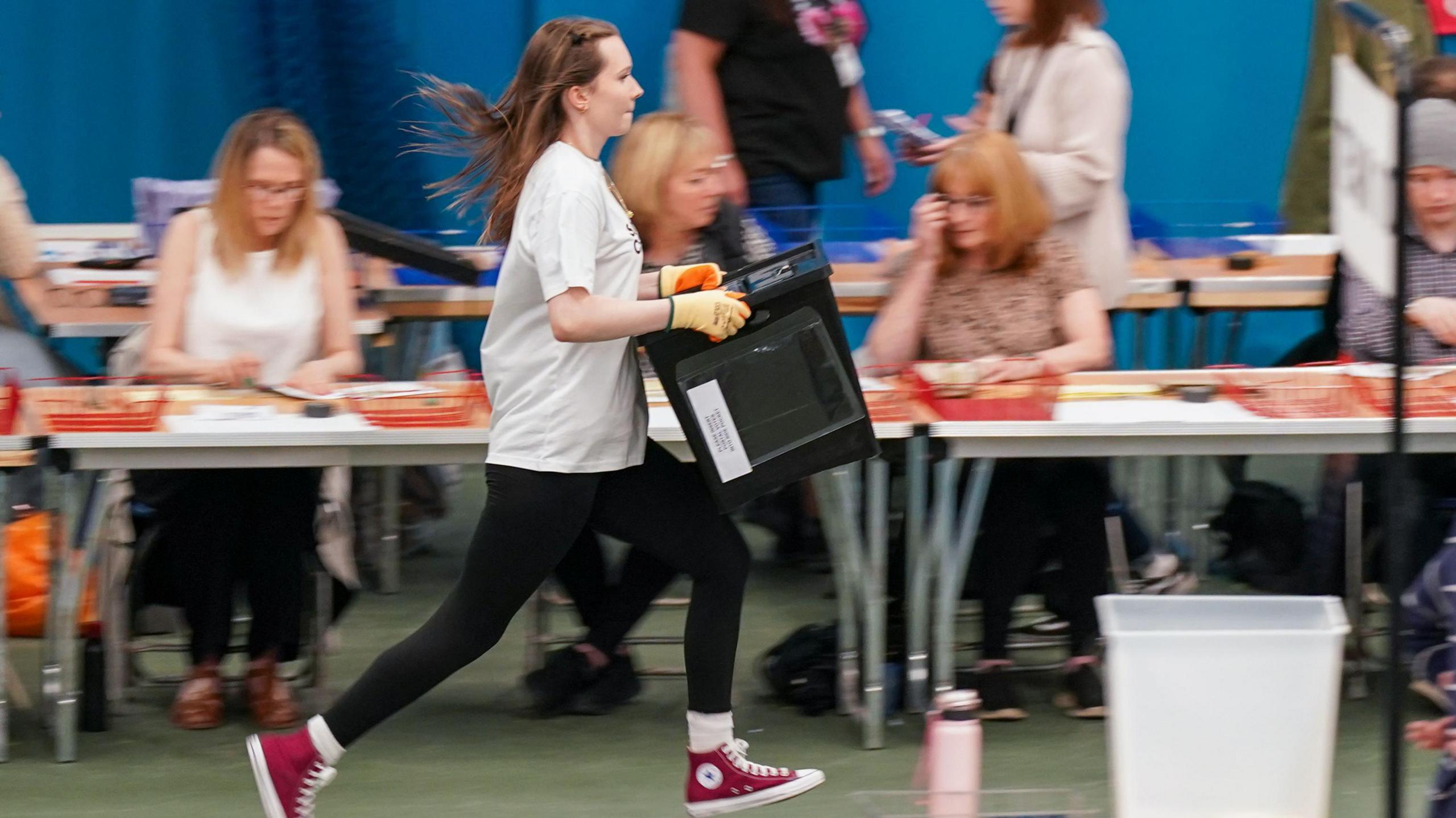 A young person running holding a ballot box