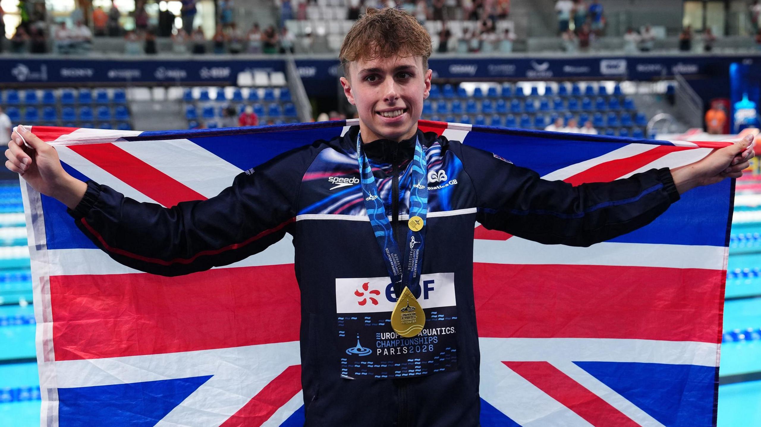 Filip Nowacki holds the Great Britain flag with his gold medal
